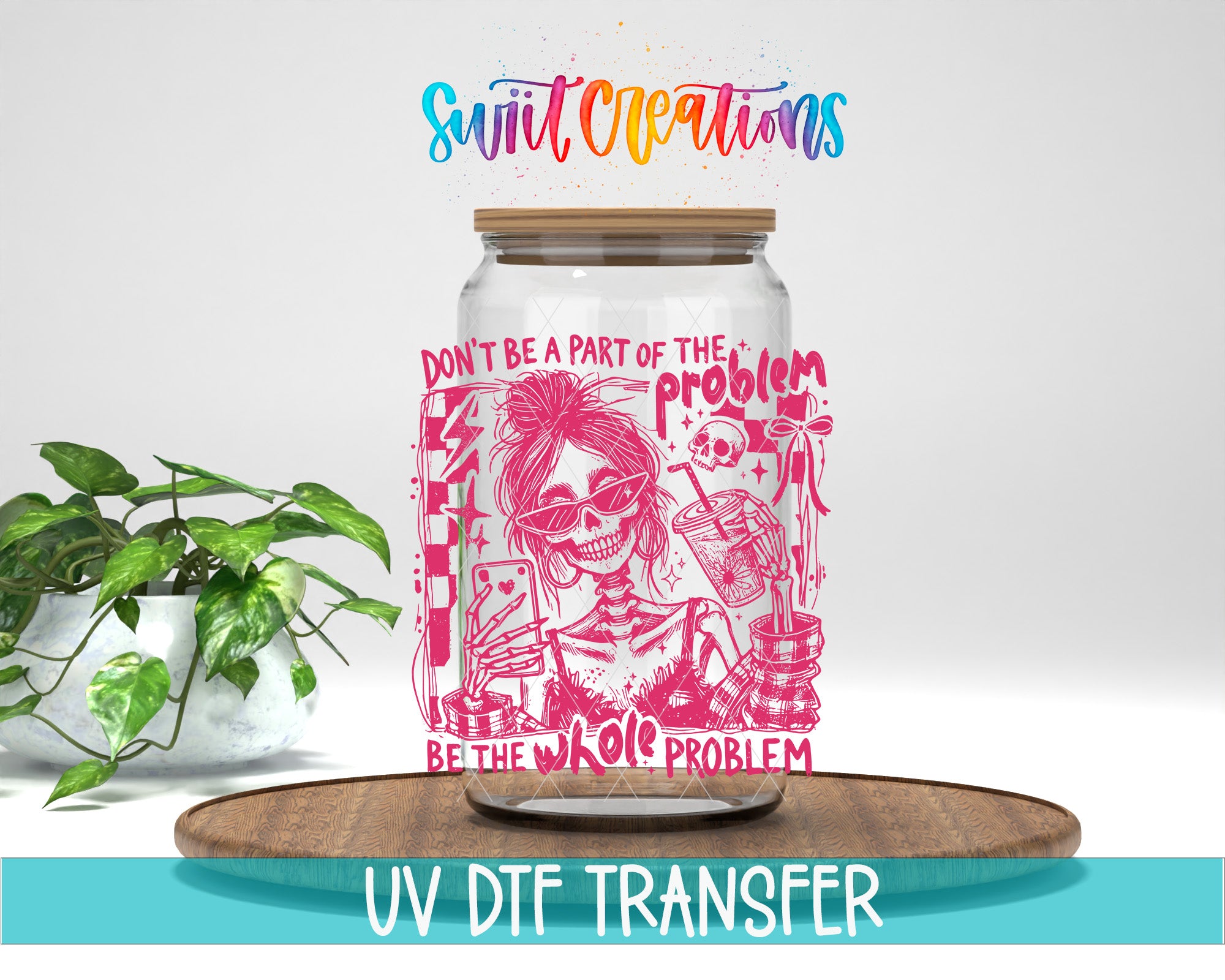 a glass jar with a pink and white design, including a skeleton and various other elements, placed on a wooden surface. The jar has a lid and a straw sticking out of it. The background of the image is white, and there is a potted plant to the left of the jar.