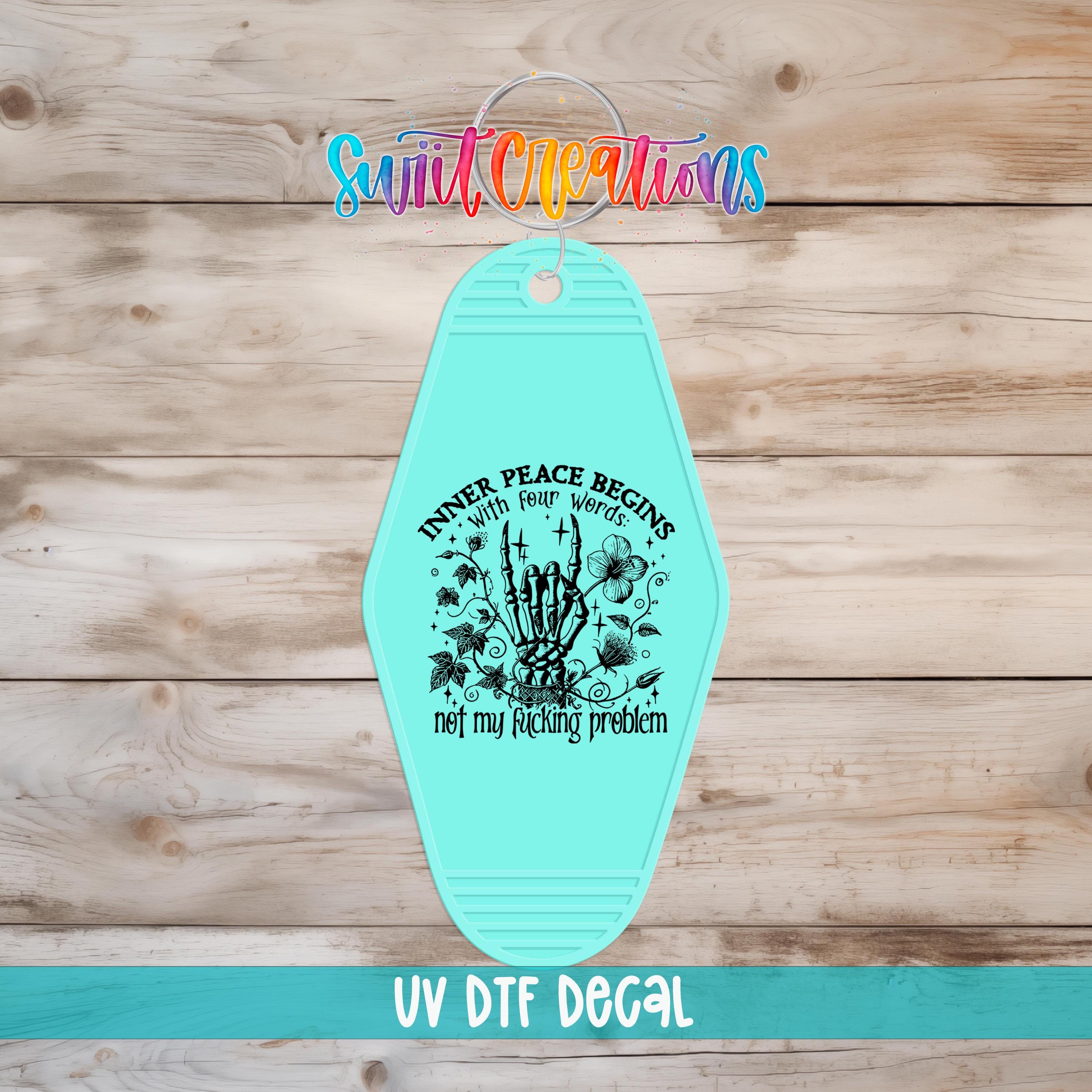 A turquoise keychain with a graphic design and text on it, placed on a wooden surface.