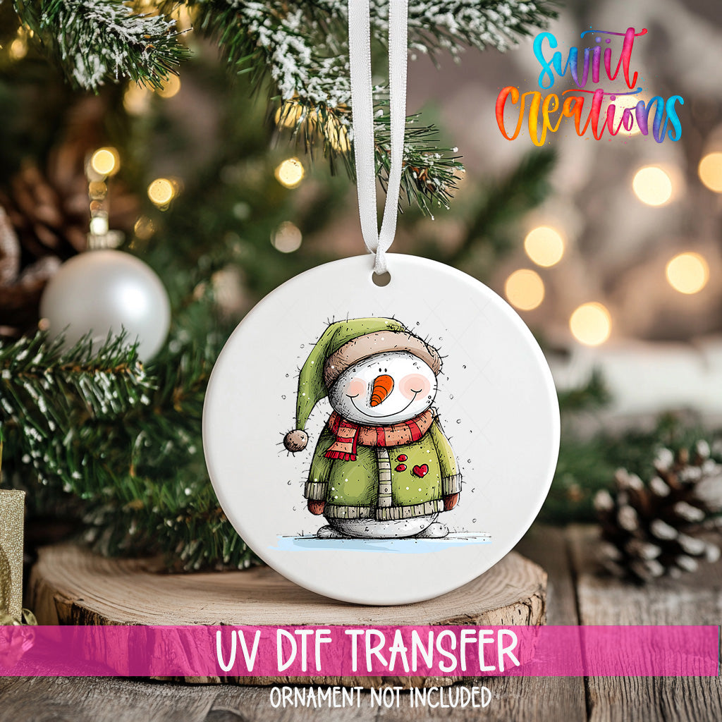 A white ceramic ornament featuring a snowman is hanging on a Christmas tree, with a blurred background of pine branches and twinkling lights.