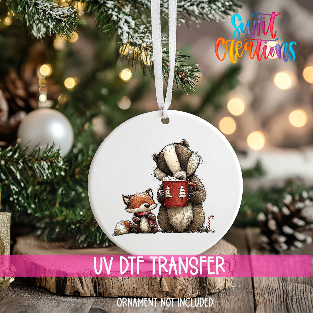 A white ornament with a picture of a cat and a bear holding a mug, hanging on a Christmas tree.