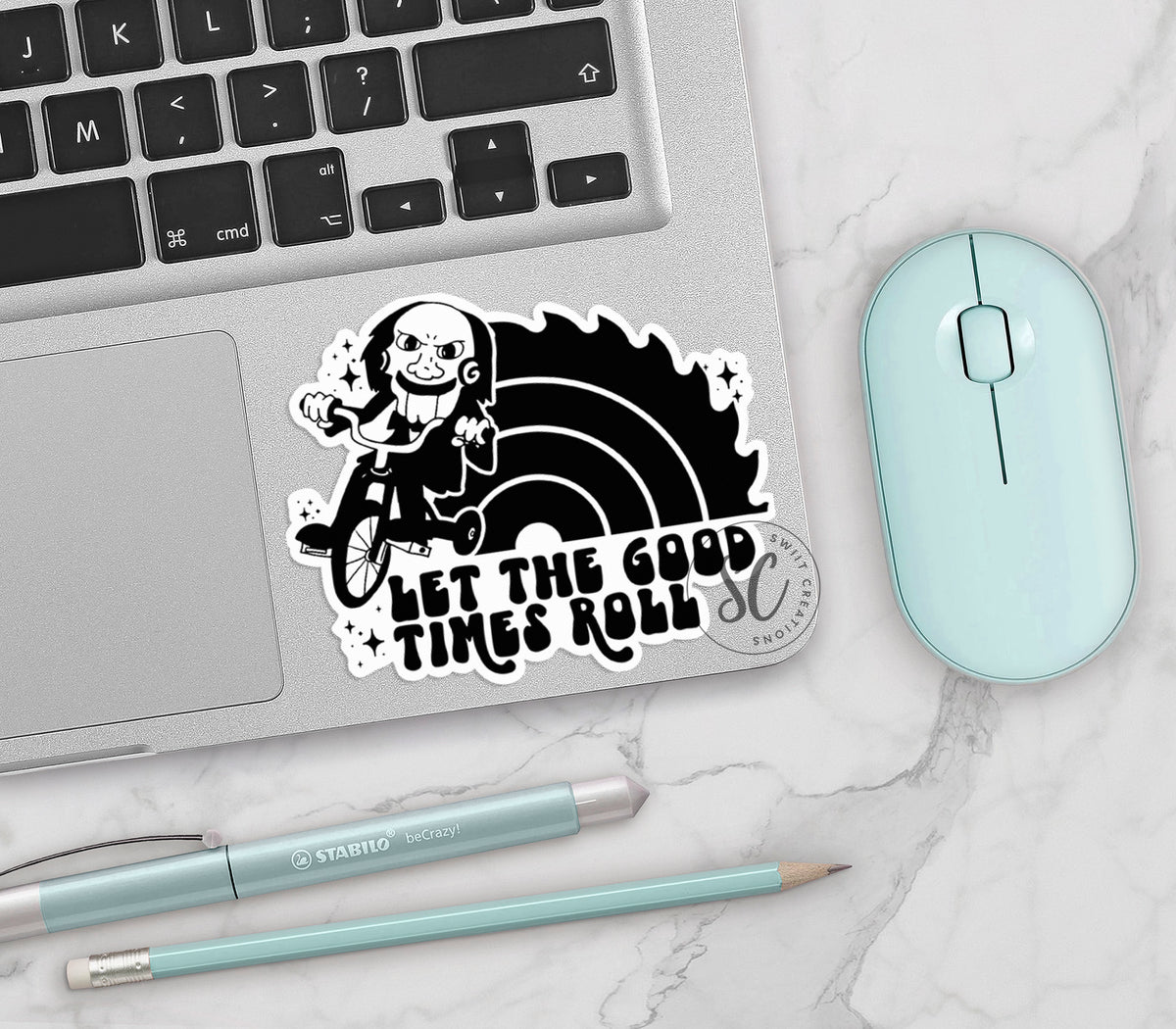 Let the Good Times Roll Horror vinyl sticker on a silver laptop next to a mint mouse and pens