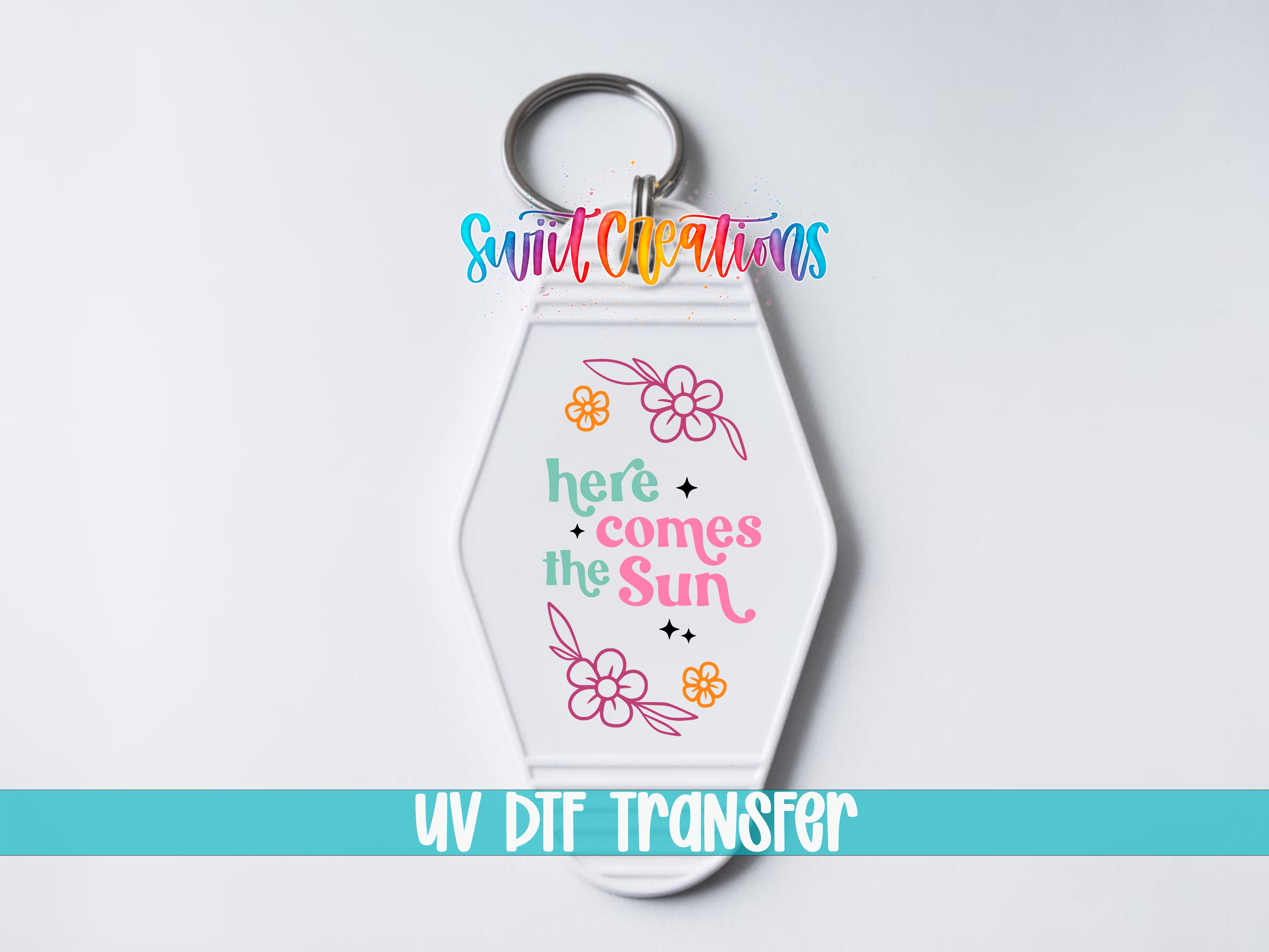 A keychain with a colorful design and text that says "here comes the sun".