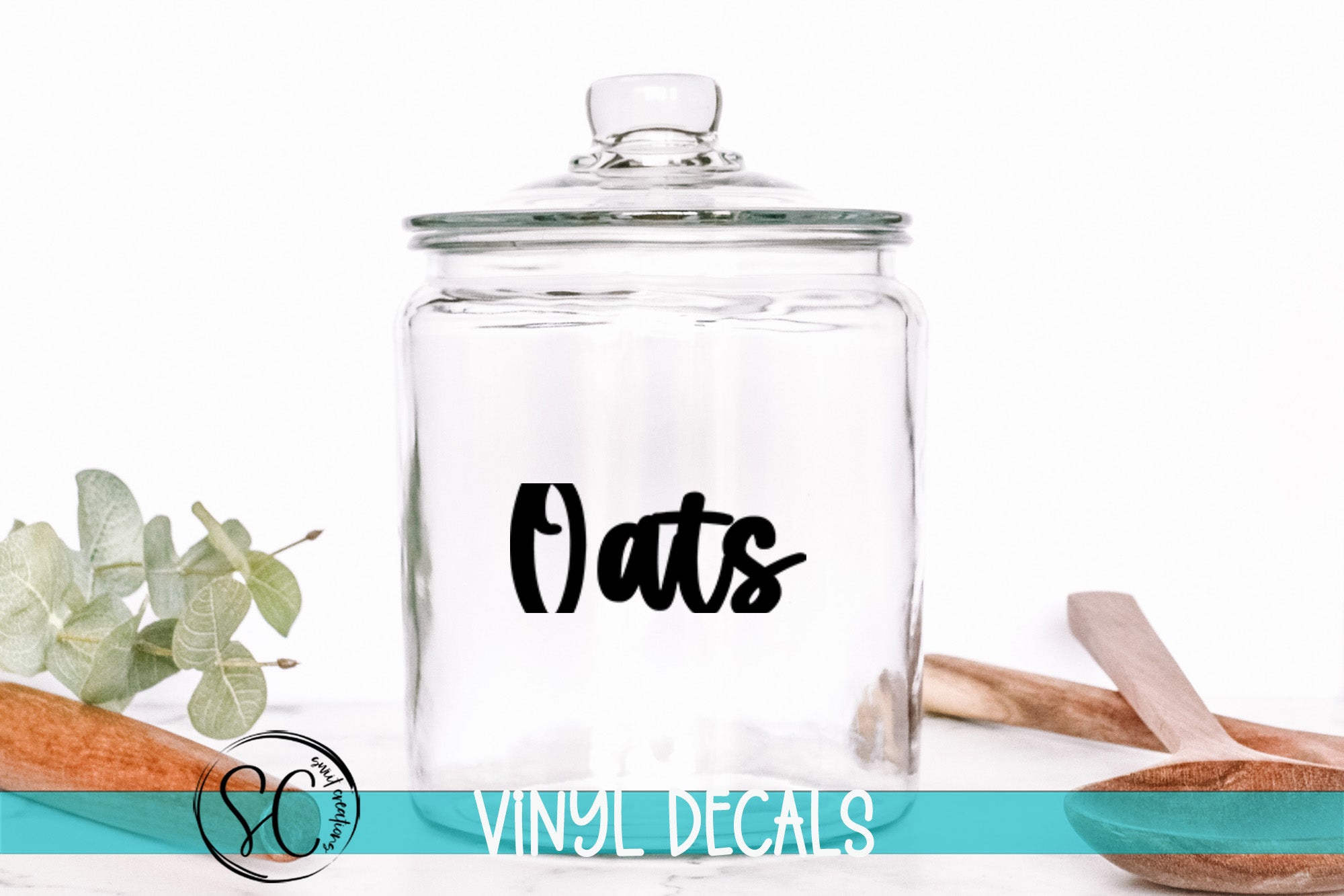 A clear glass jar with a black text label on it, placed on a white surface next to some wooden utensils.