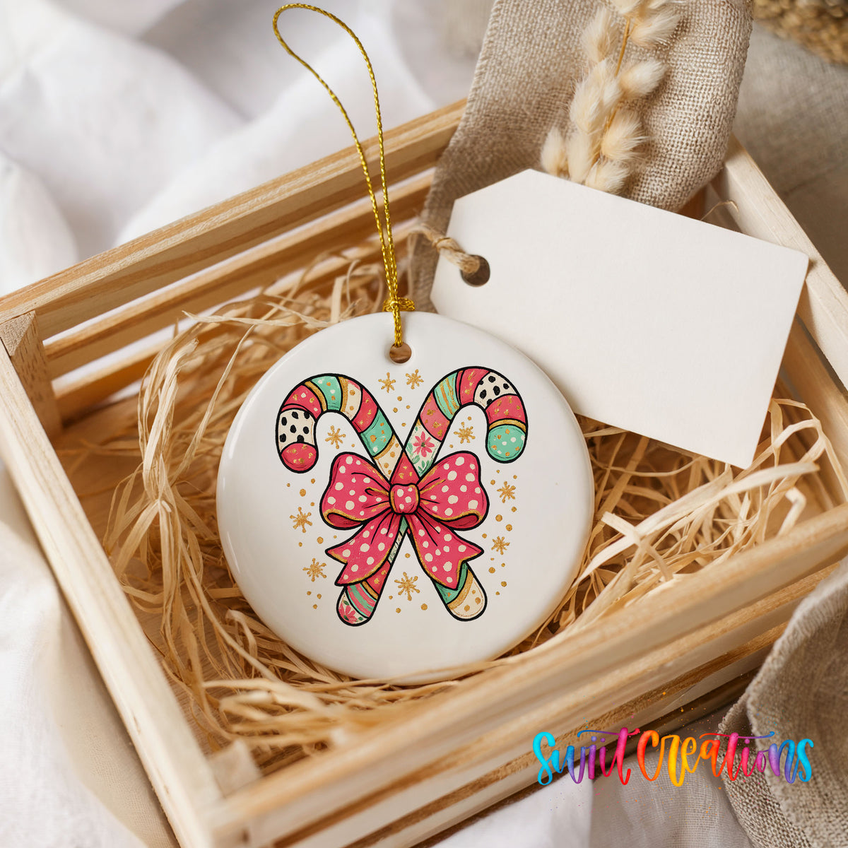 A wooden crate containing a white ceramic ornament with a colorful candy cane design and a pink bow.