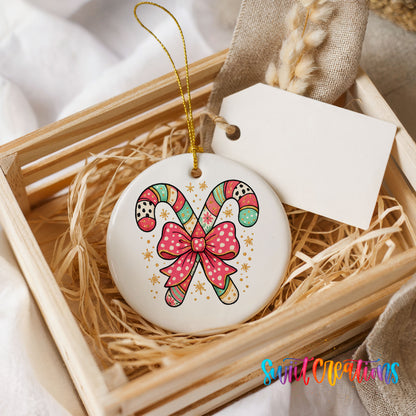 A wooden crate containing a white ceramic ornament with a colorful candy cane design and a pink bow.