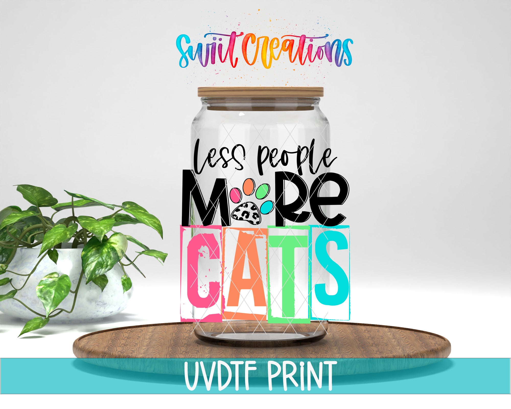 A jar with a lid, featuring a colorful and playful design with the text "Less people more cats" and a paw print. The jar is placed on a wooden surface, and there is a potted plant in the background.