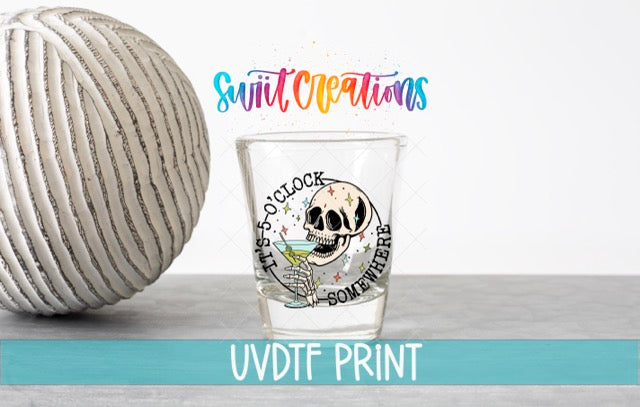 a ball of yarn next to a shot glass
