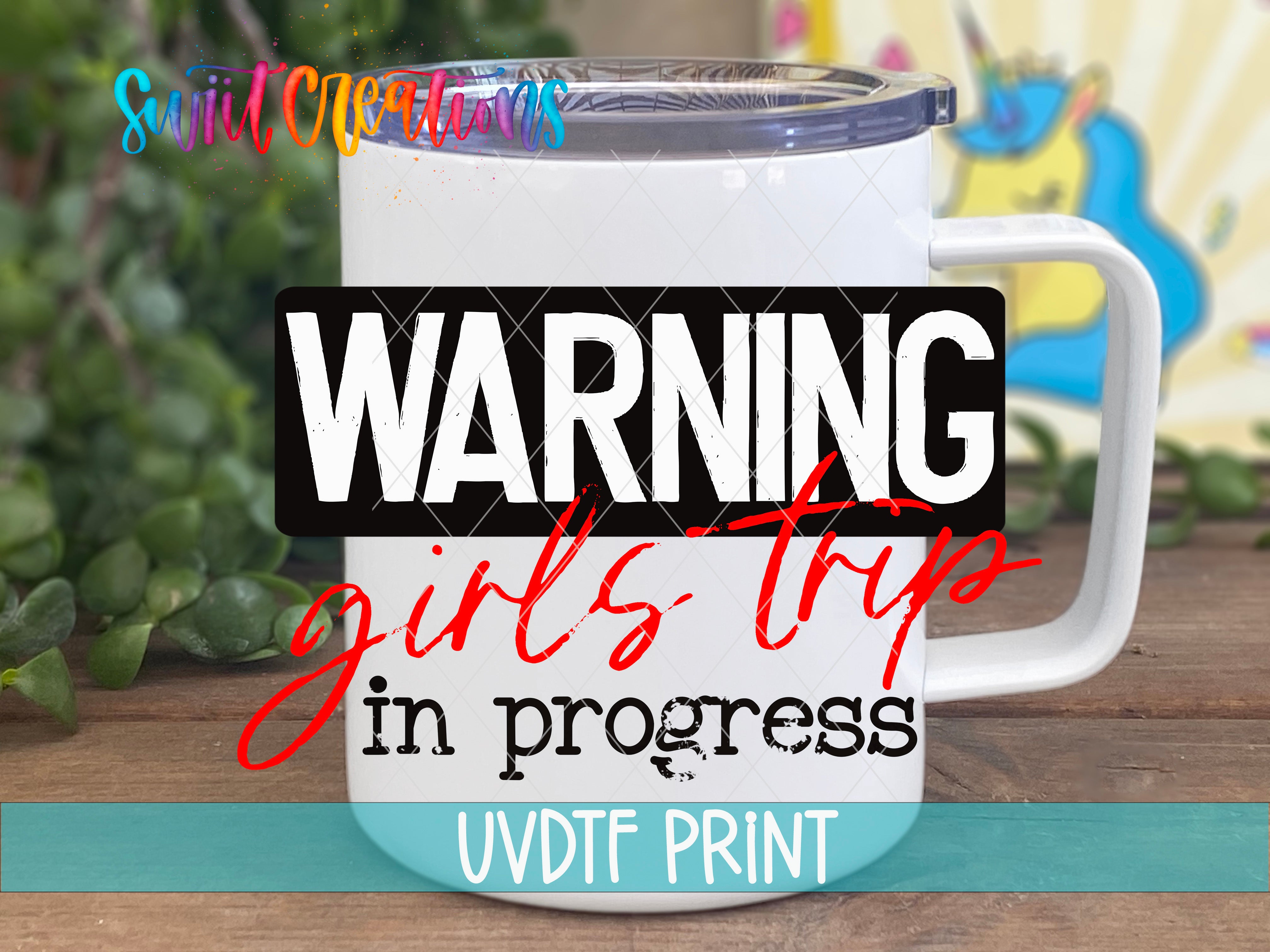 A white mug with a printed warning label on it, placed on a wooden surface with some greenery in the background.