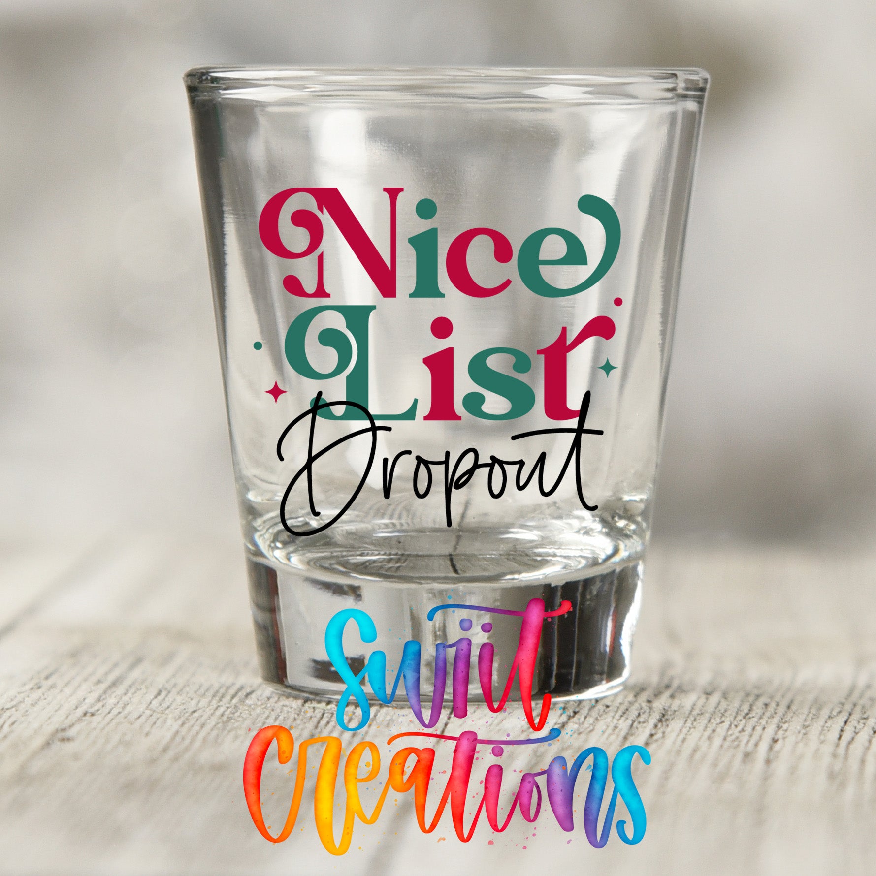 a shot glass with text on it, placed on a wooden surface.