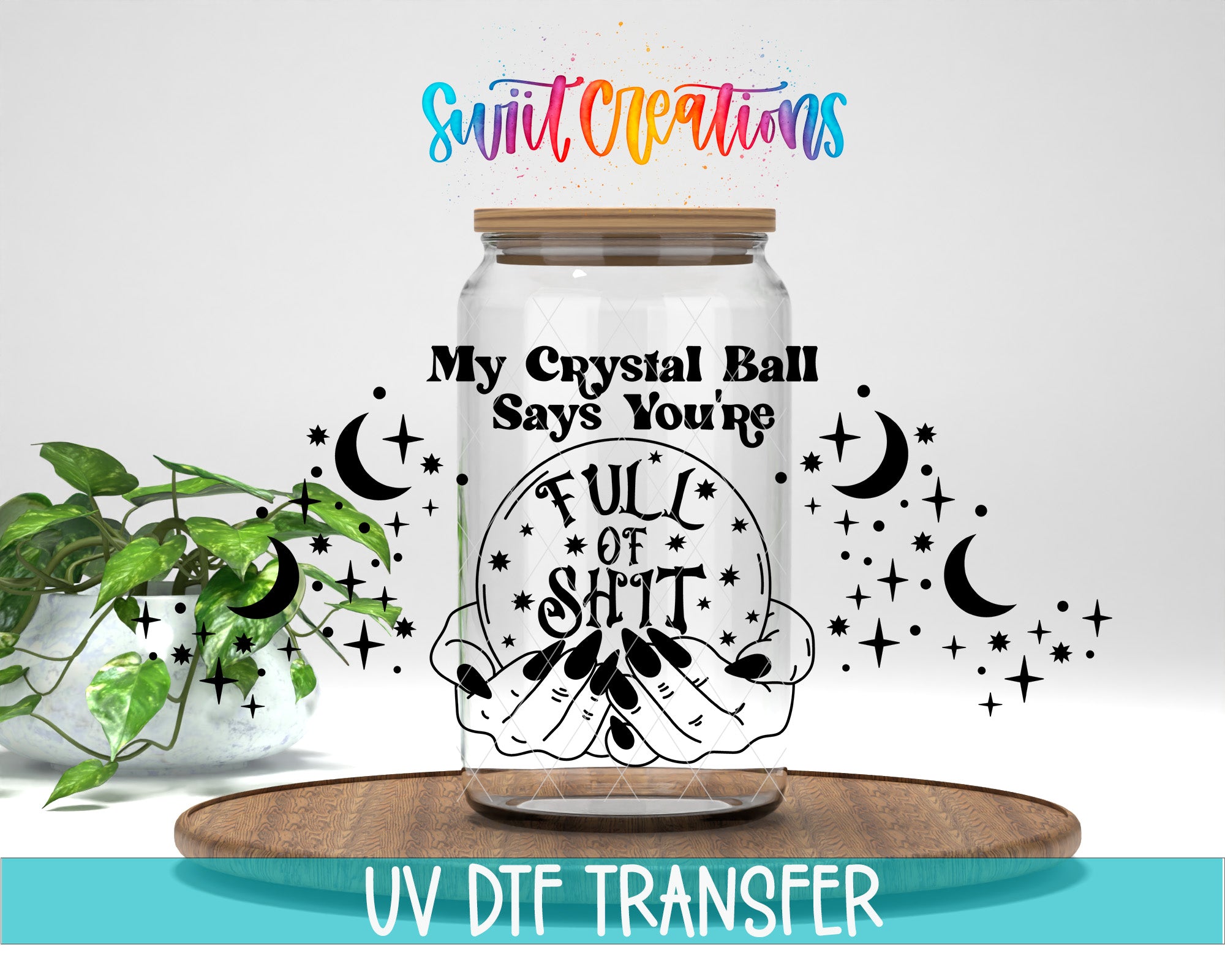 a clear glass jar with a label that says "My Crystal Ball Says You're Full of Shit" and is surrounded by various symbols, including stars, crescent moons, and a crystal ball. The jar is placed on a wooden surface, and there is a potted plant in the background.