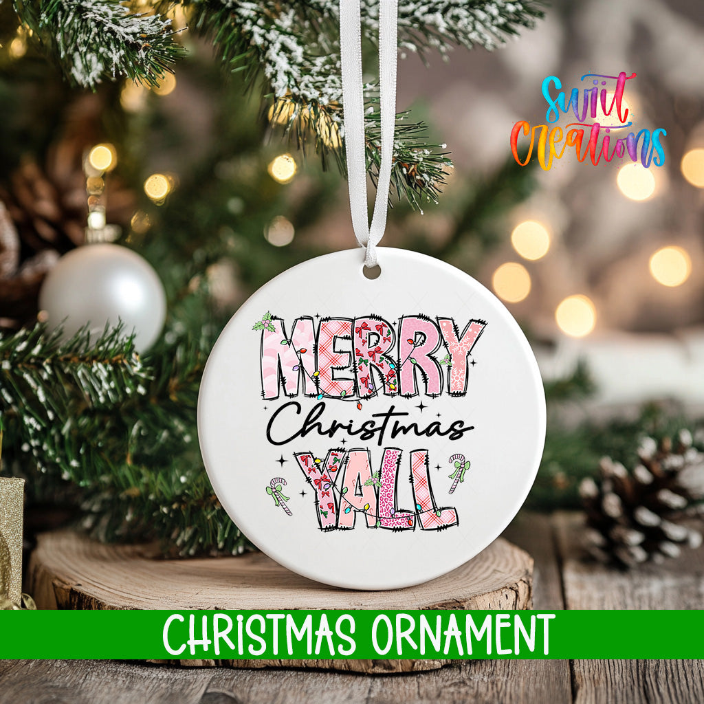 A white Christmas ornament with the text "Merry Christmas Y'all" printed on it, hanging from a tree branch.