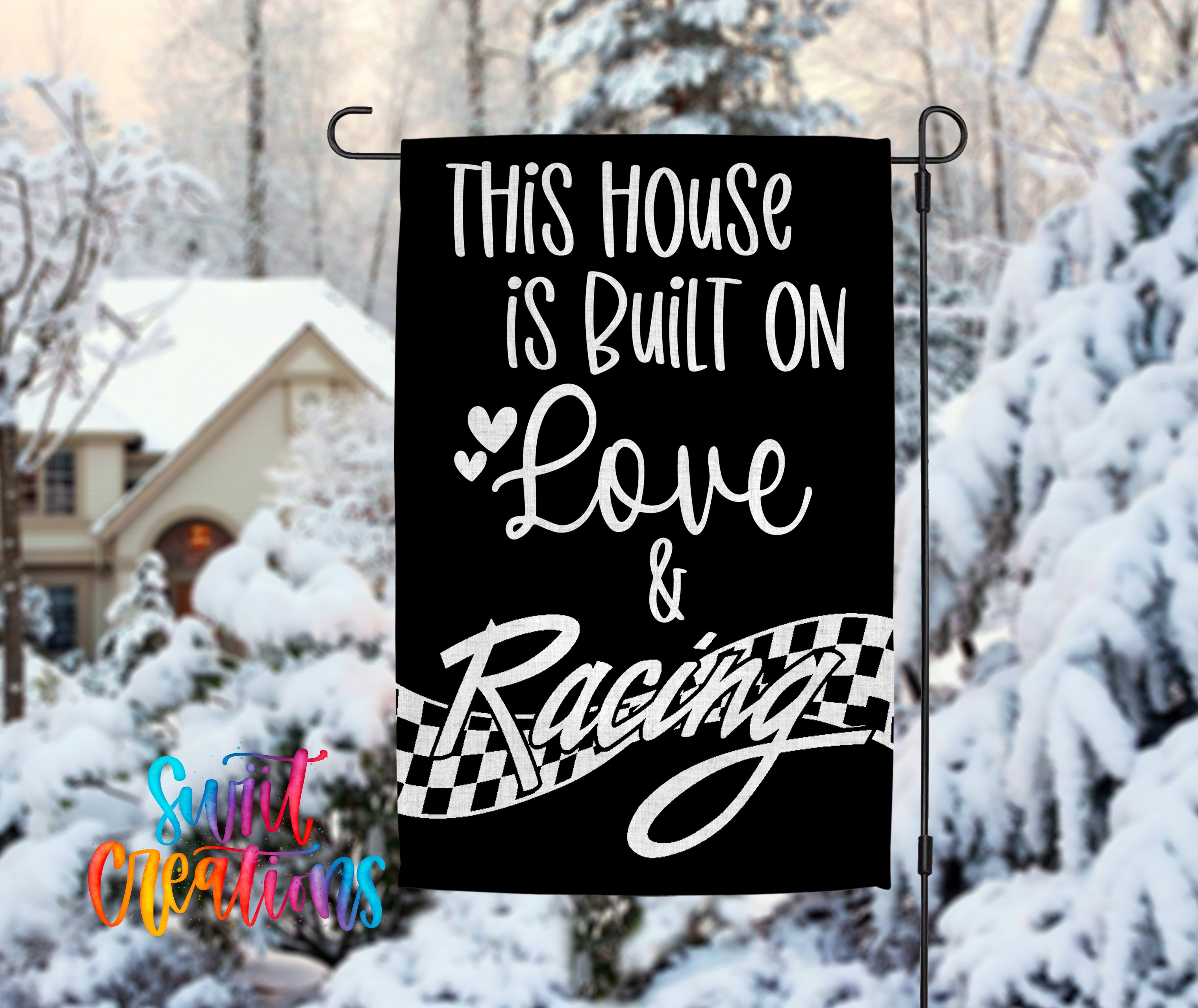 A black and white garden sign with the text "This house is built on love & racing" displayed prominently.