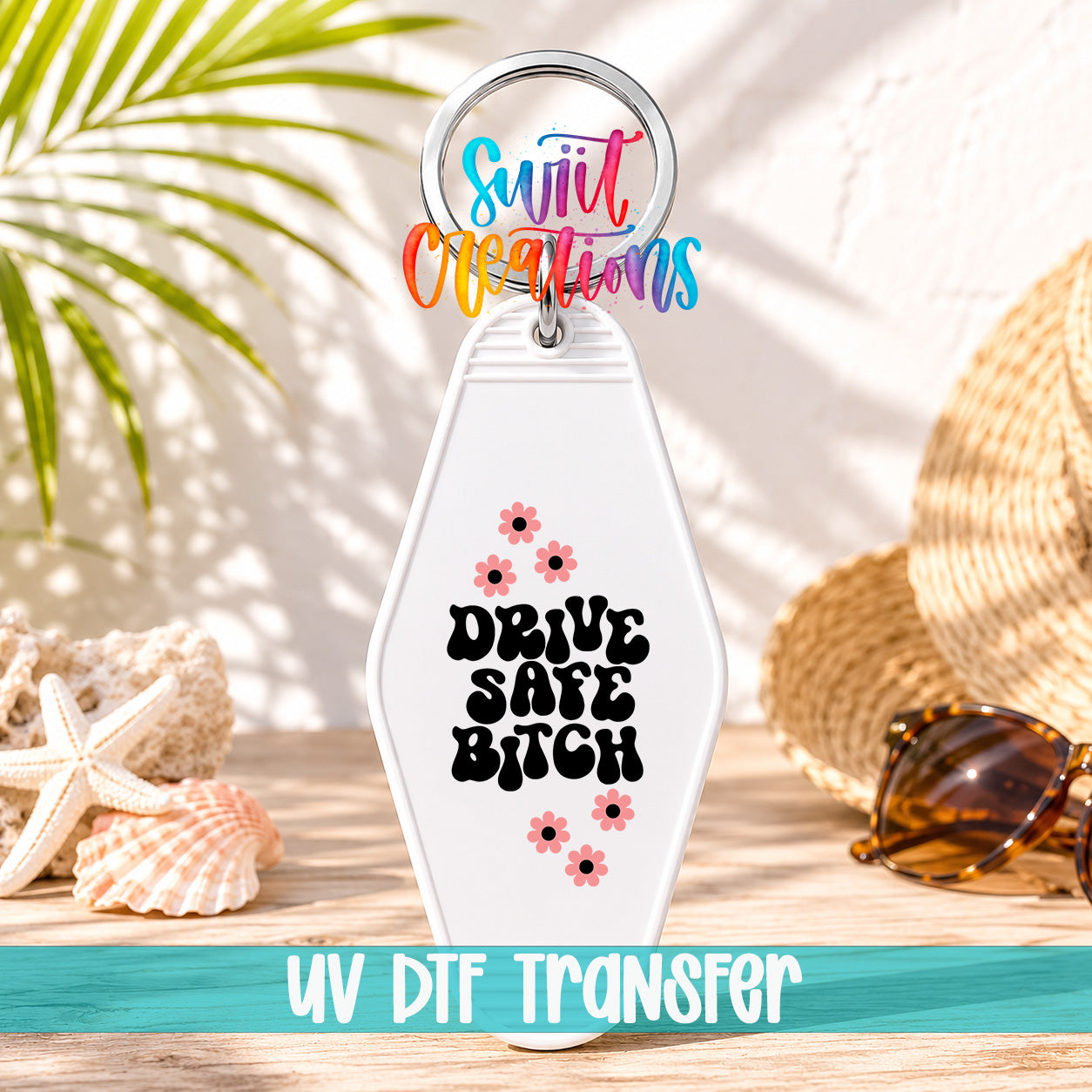 A keychain with a colorful design and text, placed on a wooden surface with sunglasses and a straw hat in the background.