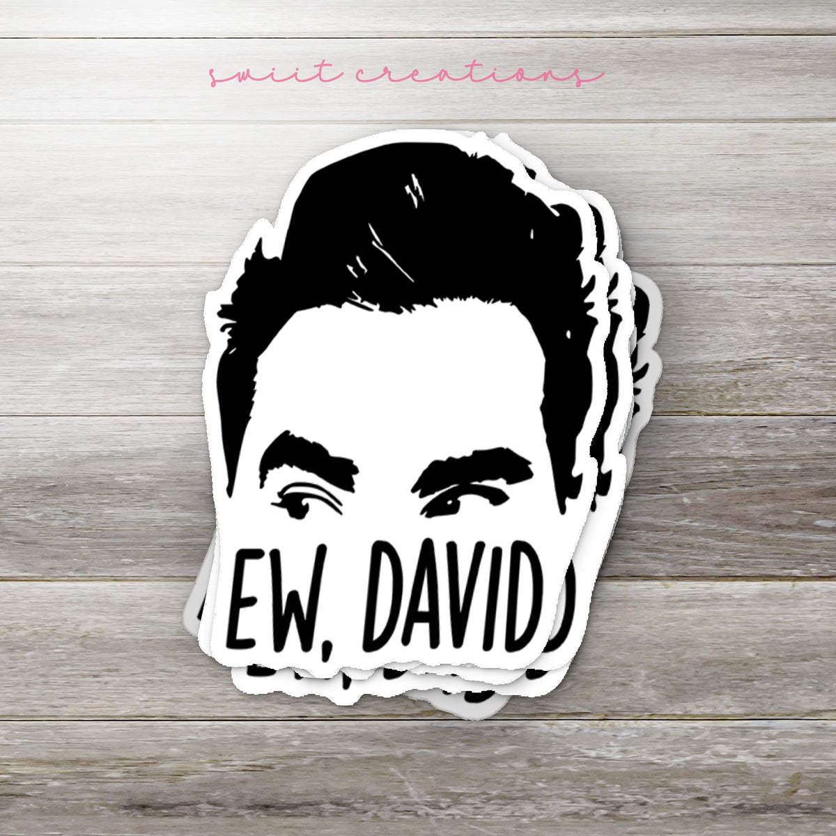 Stack of Ew David glossy stickers on a gray wood table