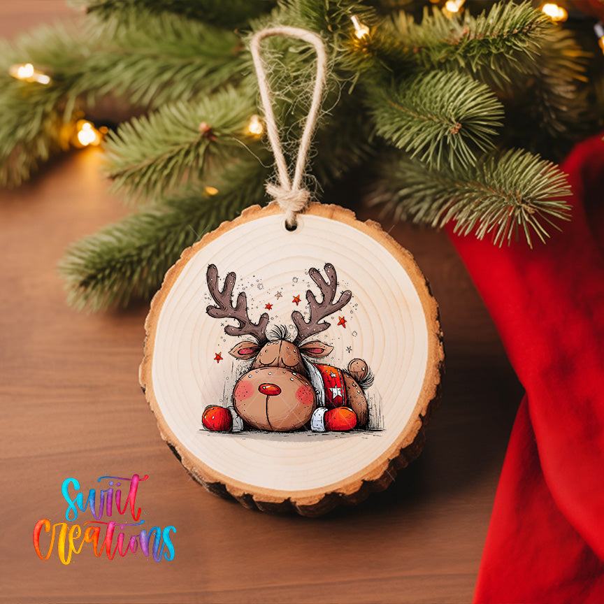 A wooden ornament featuring a cartoon reindeer is hanging on a Christmas tree, surrounded by pine branches and twinkling lights.