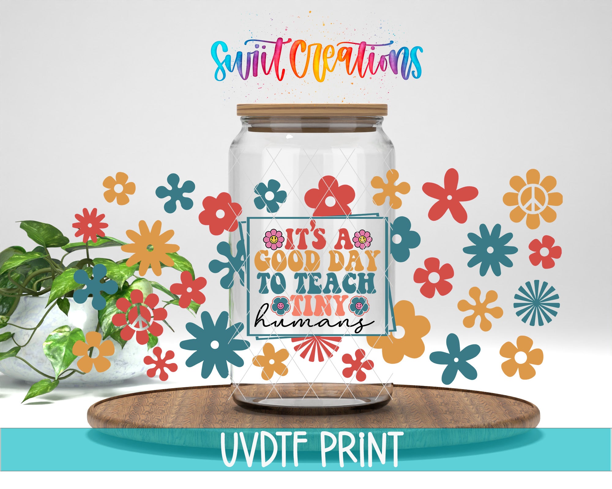a clear glass jar with a label that says "It's a good day to teach tiny humans", surrounded by colorful flower decals. The jar is placed on a wooden tray, and there is a potted plant in the background.