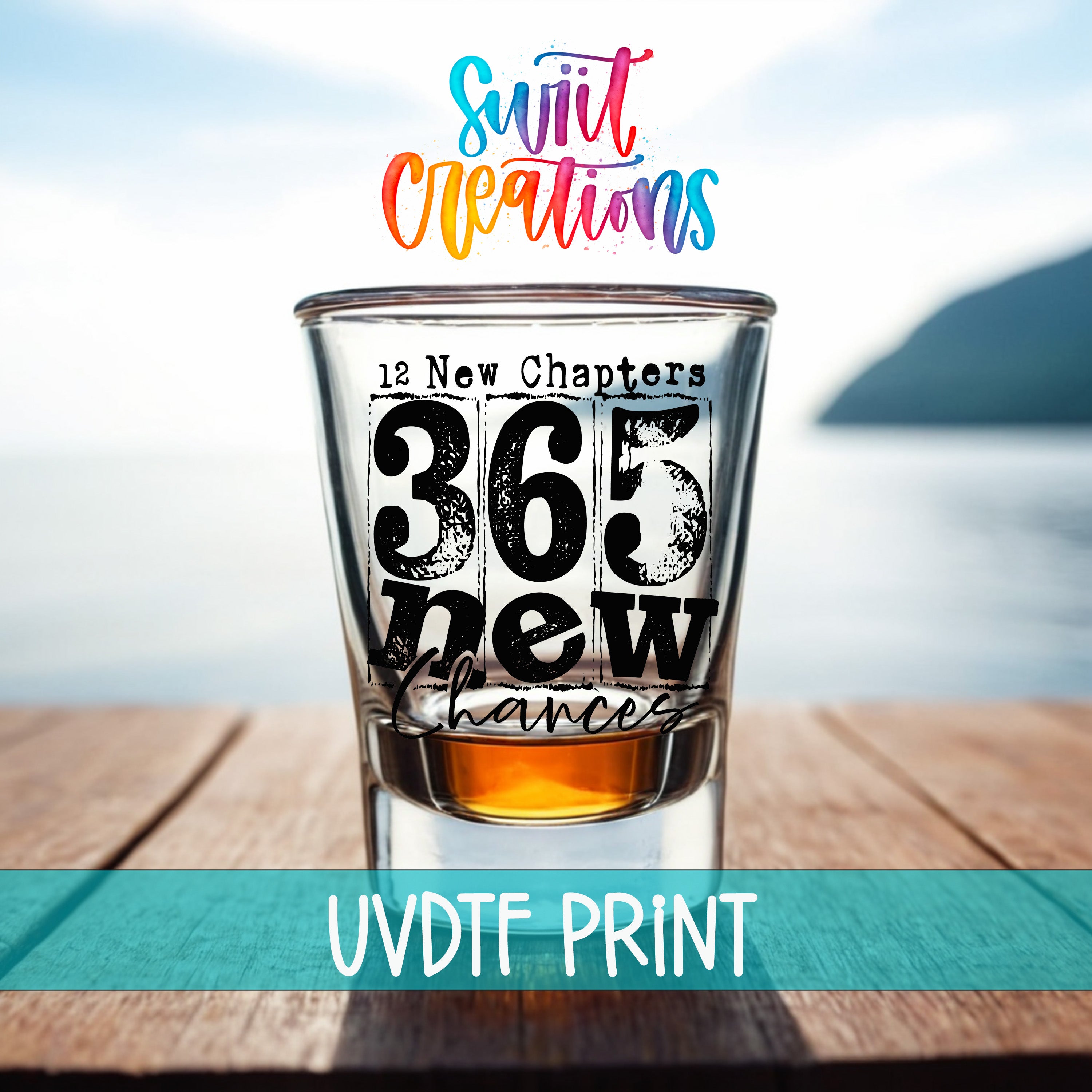 a shot glass with the text "365 New Chapters" printed on it, placed on a wooden surface with a body of water in the background.