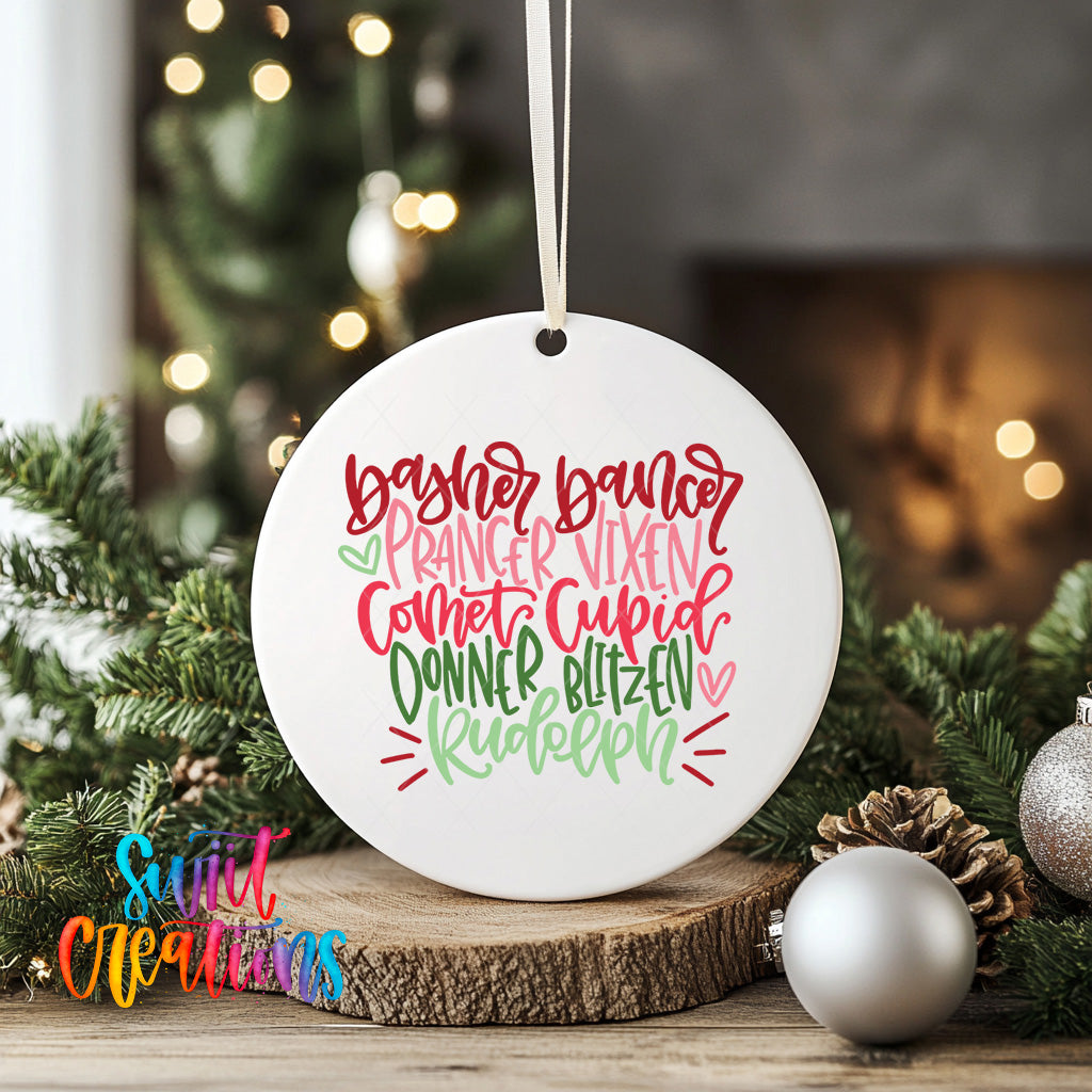 A white ceramic ornament with a festive design hangs on a wooden surface, surrounded by Christmas decorations and greenery.