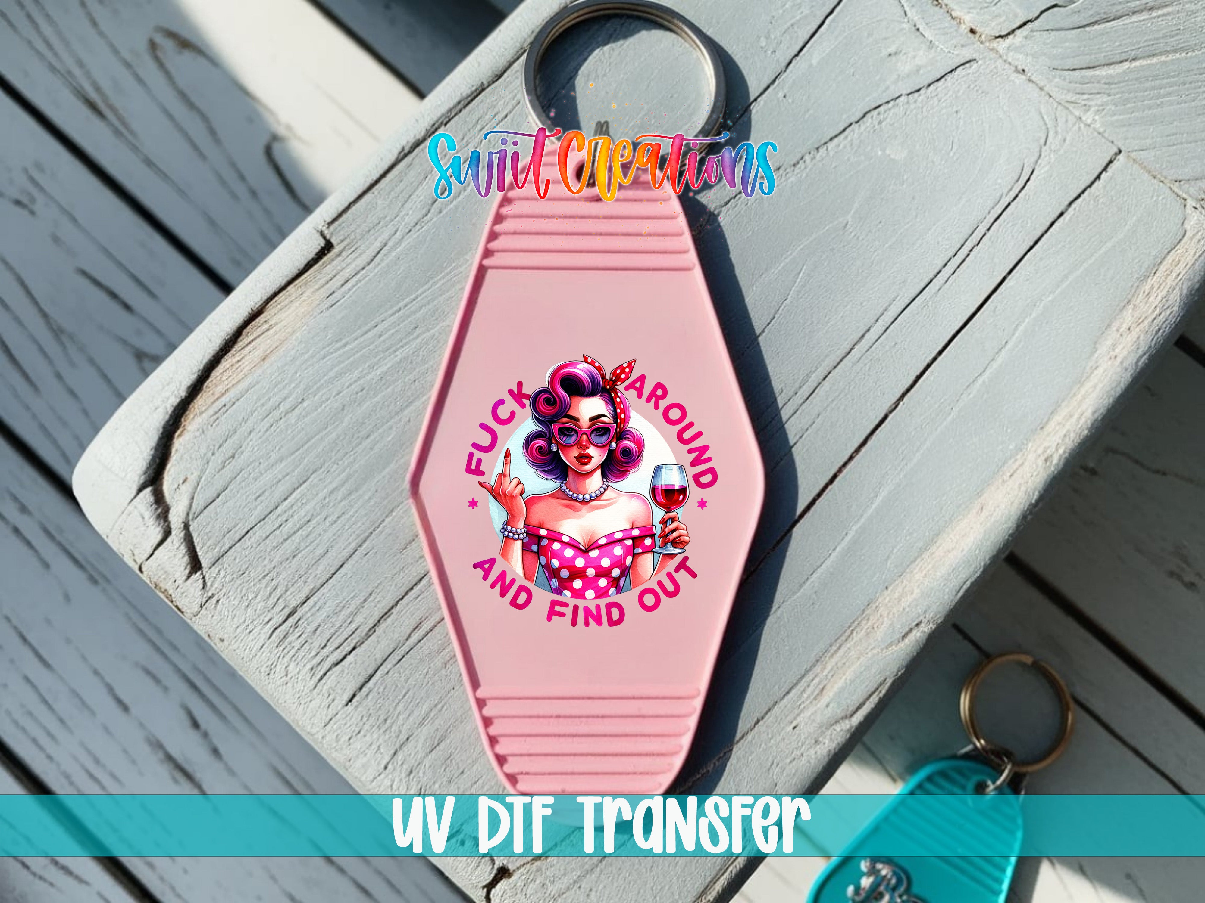 A pink keychain with a cartoon illustration of a woman and the text "FUCK AROUND AND FIND OUT" printed on it.