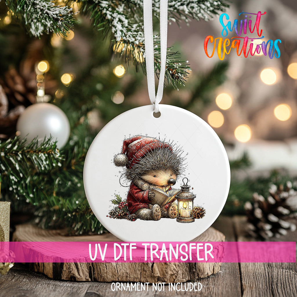 A white ornament with a hedgehog wearing a red hat and holding a lantern, hanging on a Christmas tree.