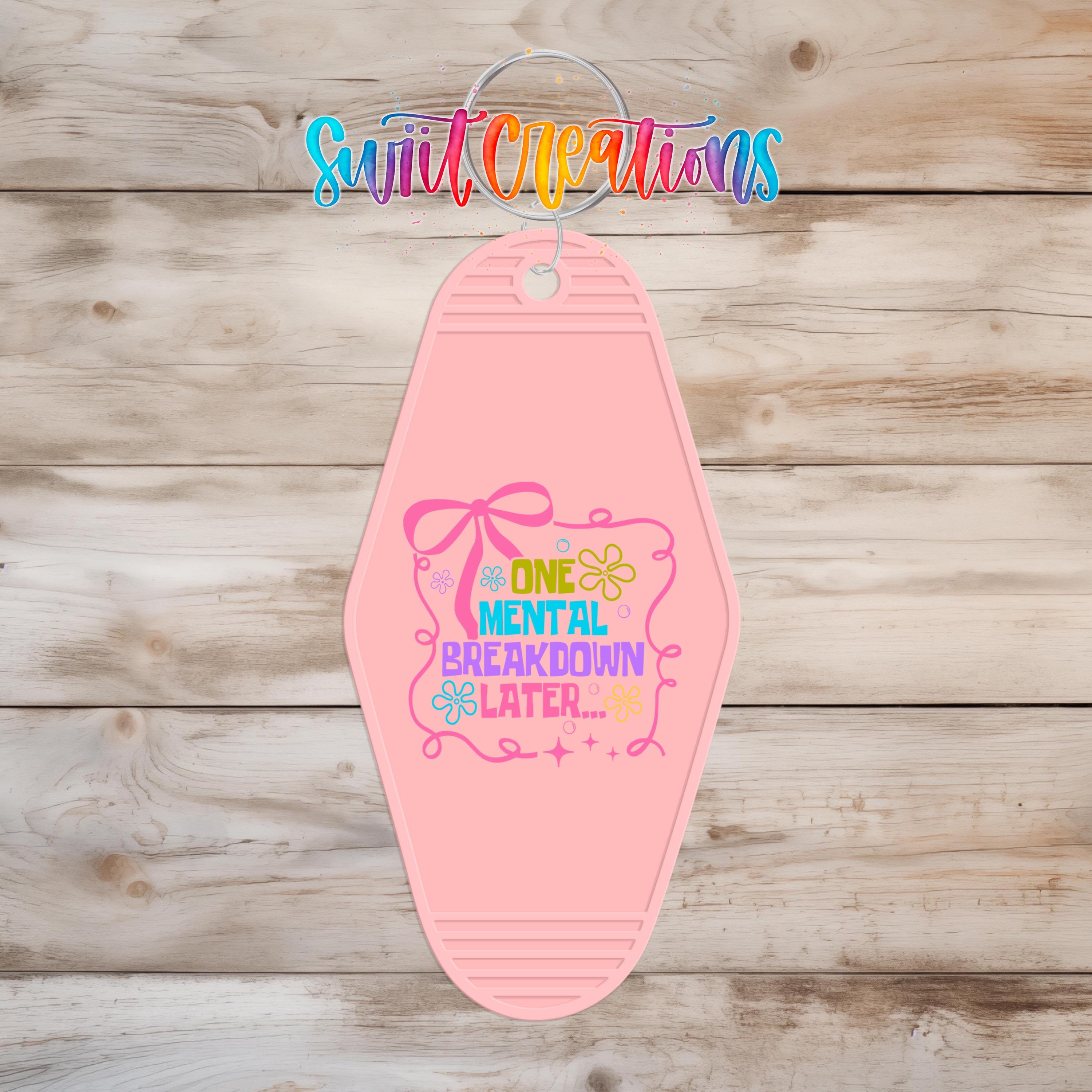 A pink keychain with a colorful design and text that says "A ONE MENTAL BREAKDOWN LATER..."