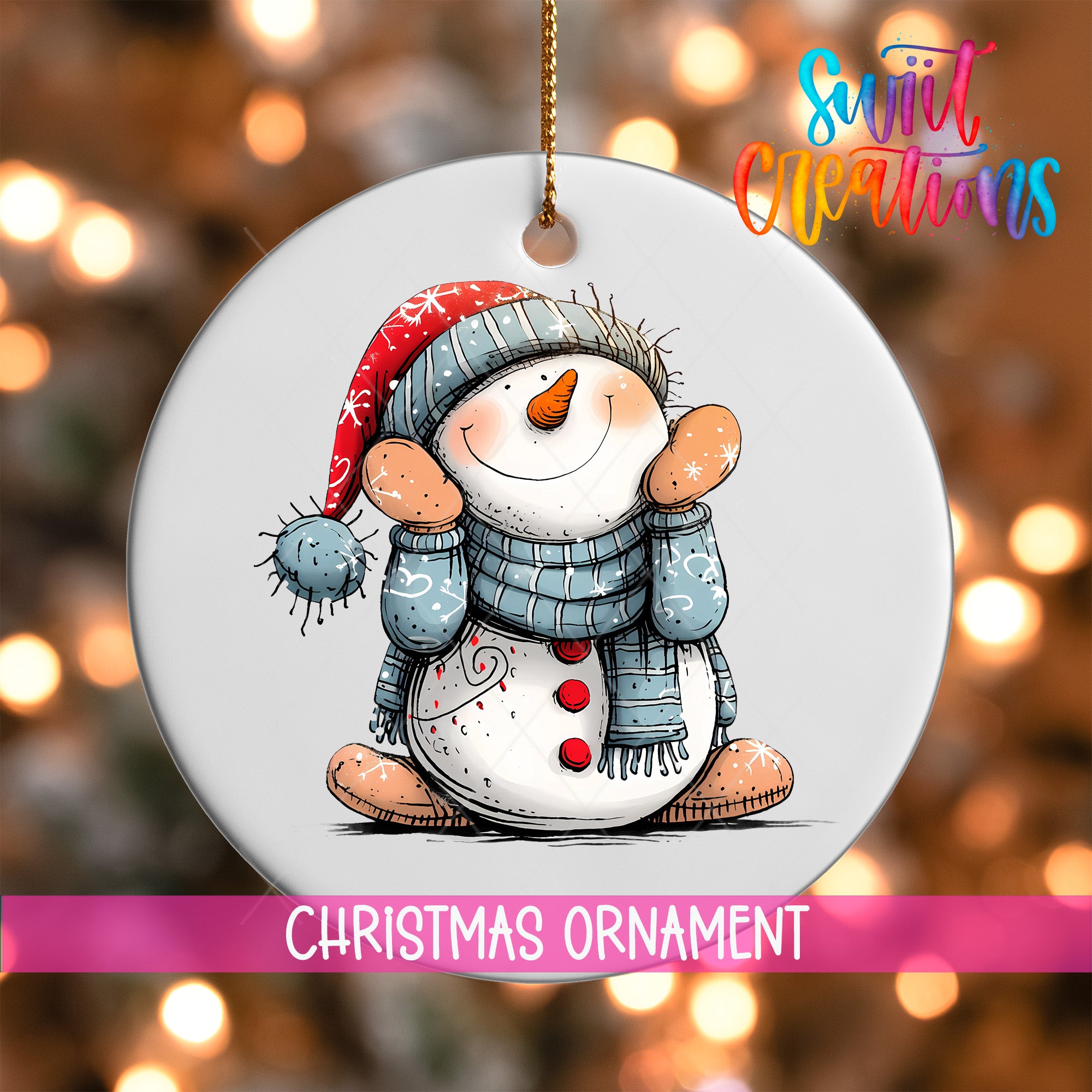 A white Christmas ornament featuring a smiling snowman wearing a red hat and blue scarf, with a pink ribbon around the ornament.