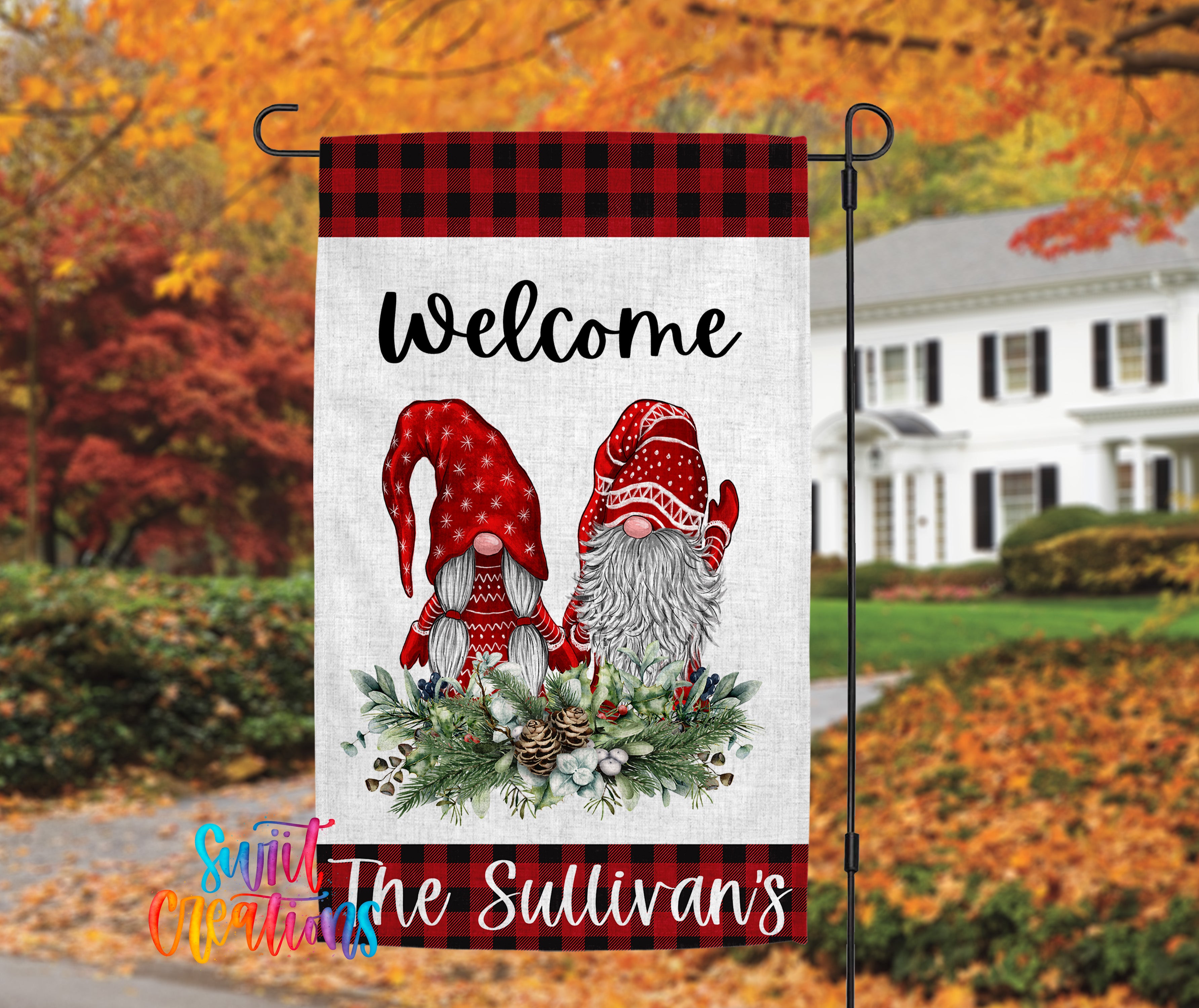A banner with a welcoming message featuring two gnomes, one wearing a red hat and the other wearing a red hat with a white stripe, standing on a bed of pine cones and greenery. The banner is displayed outdoors, with a house and trees visible in the background.