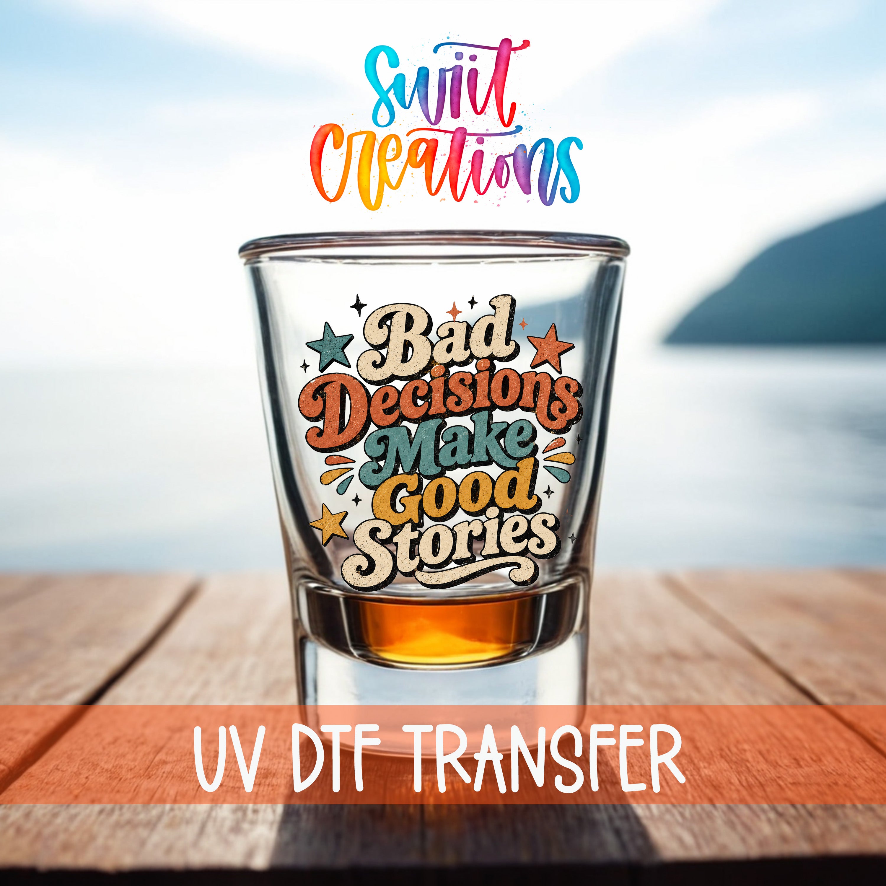 a shot glass with a colorful, hand-lettered quote on it, placed on a wooden surface with a body of water in the background.