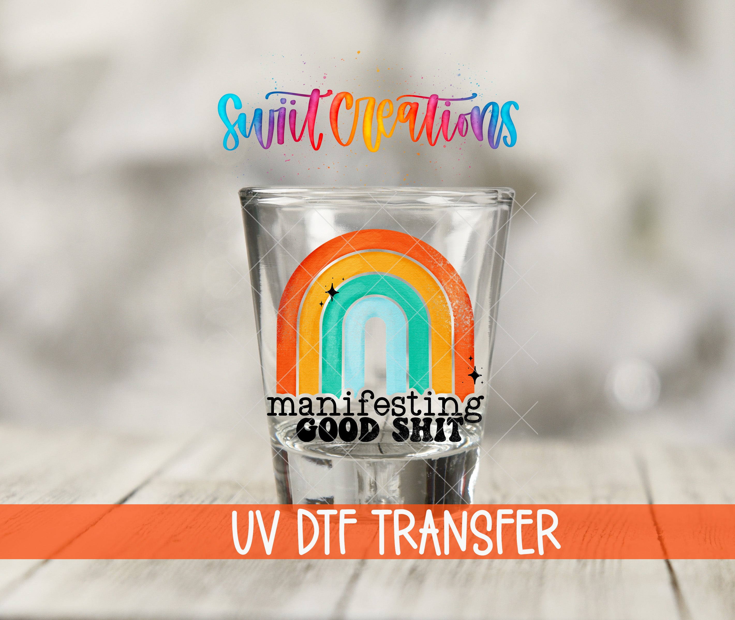 A shot glass with a rainbow design and the text "manifesting good shit" printed on it, along with the text "UV Dtf Transfer" below it.