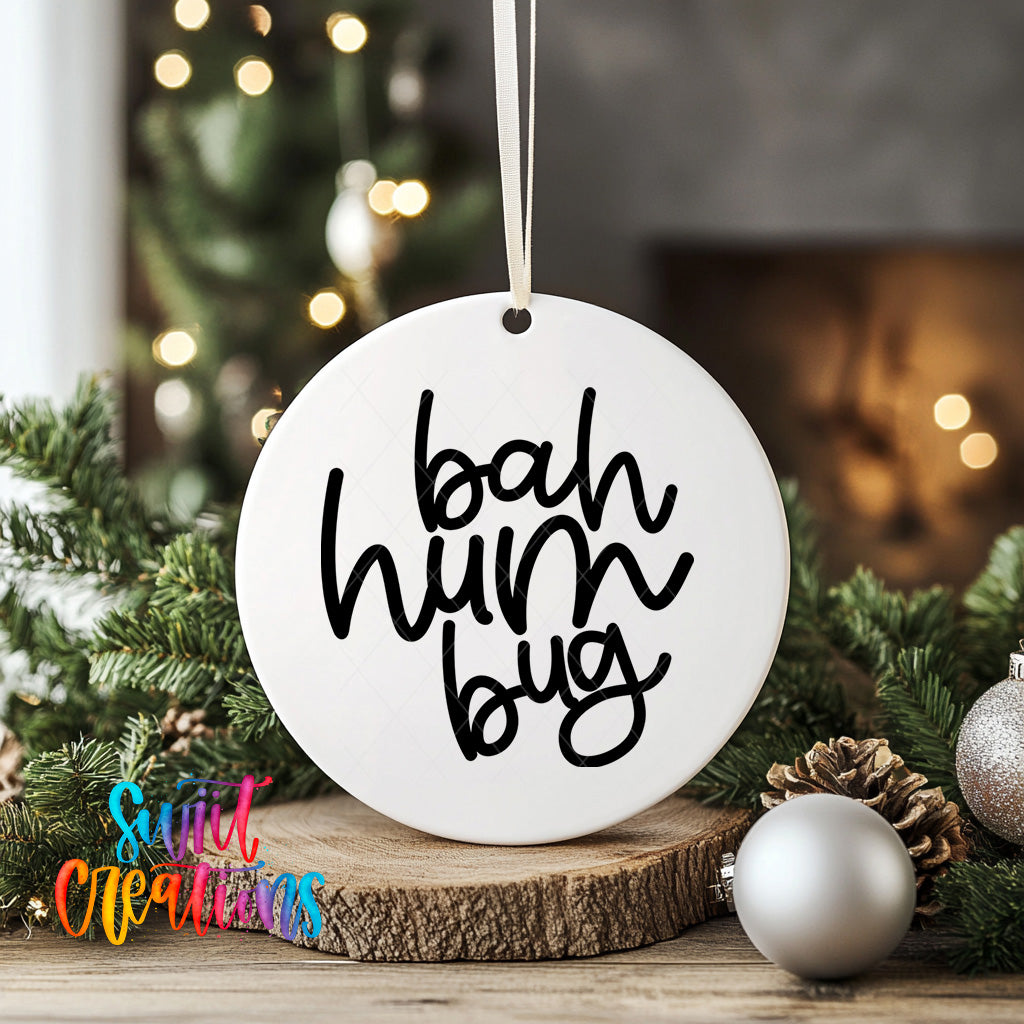 A white ornament with the text "bah hum bug" hanging from a string, surrounded by Christmas decorations such as pine branches and ornaments.