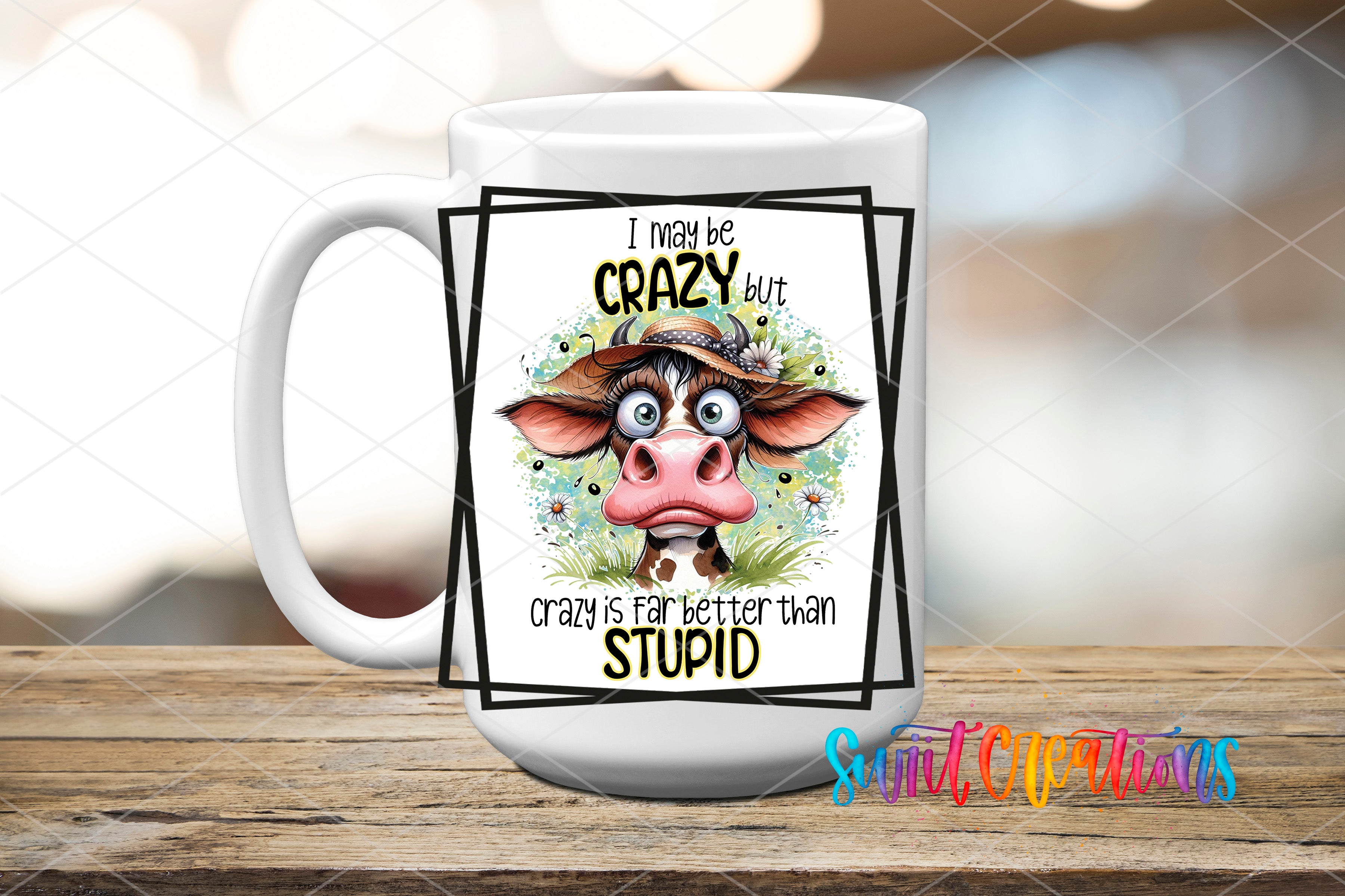 A white mug with a cartoon cow design and text on it, placed on a wooden surface.