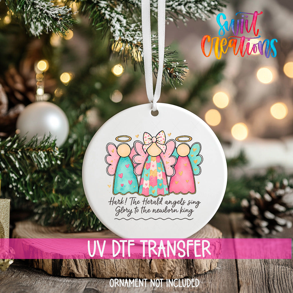 A Christmas ornament with three angelic figures and a text message, hanging on a tree.