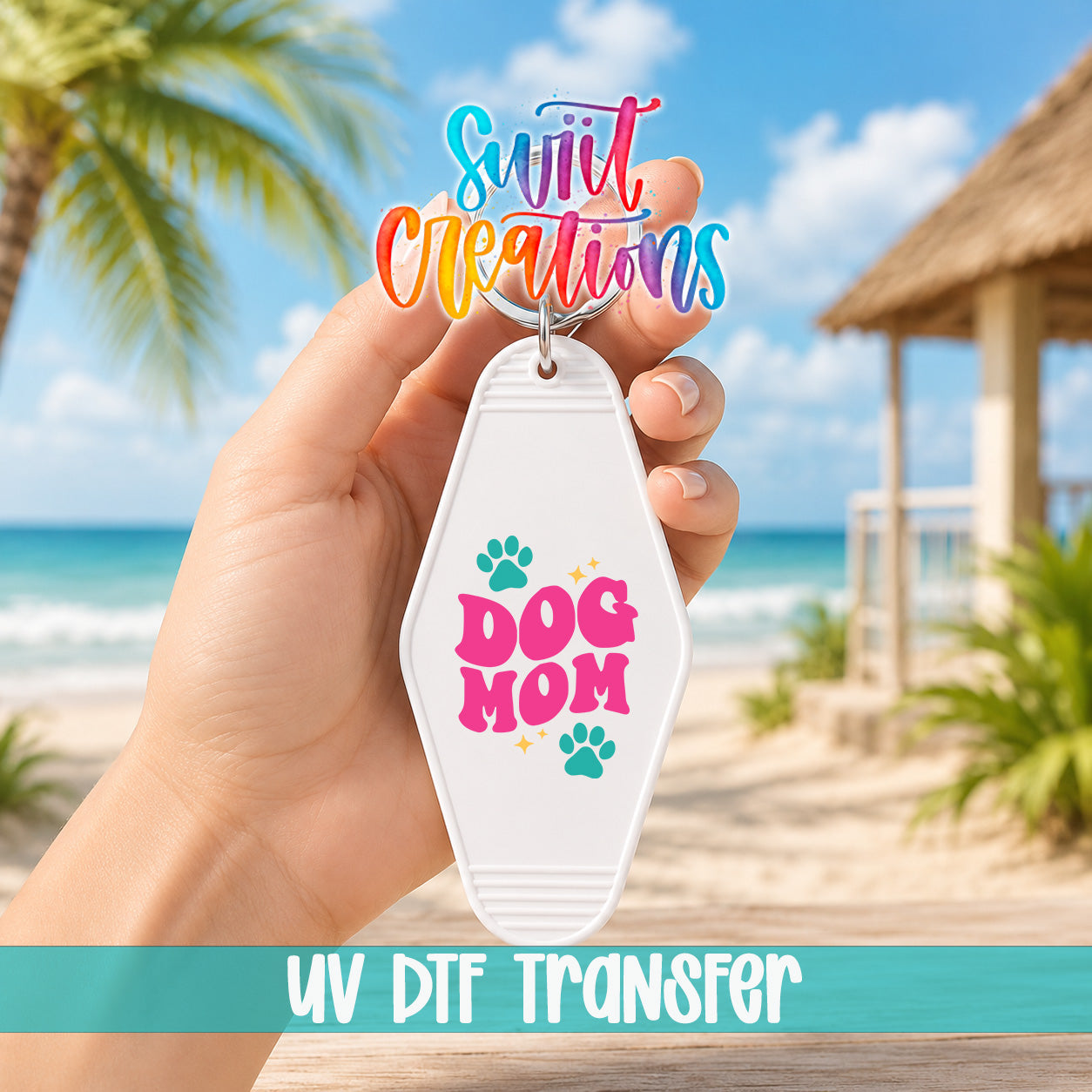 A hand holding a keychain with the text "Dog Mom" and paw prints, with a tropical beach and palm trees in the background.