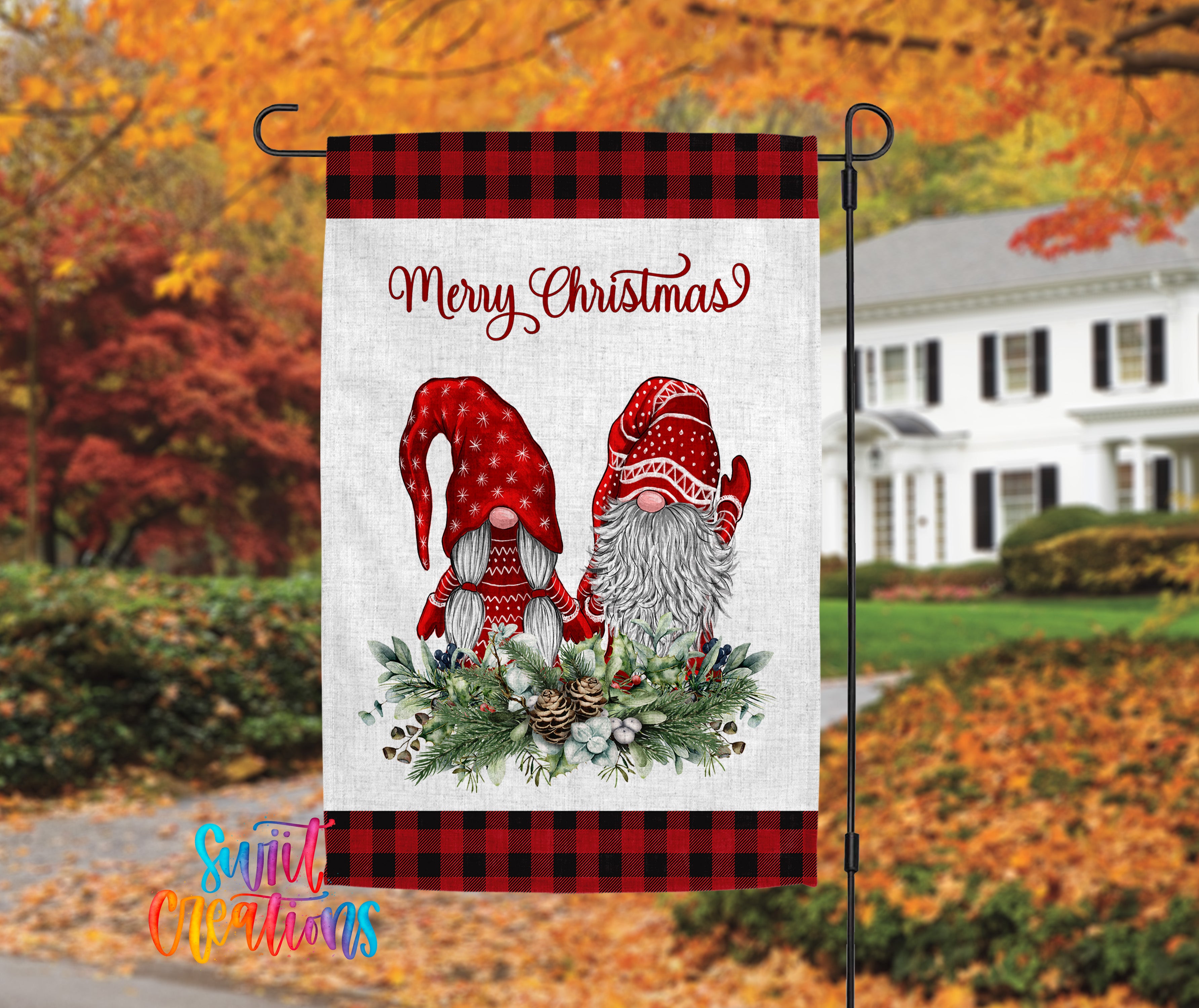 A banner with a Christmas-themed design featuring two gnomes wearing red hats and scarves, surrounded by a wreath of pine cones and other holiday decorations. The banner is hanging outside a house with autumn foliage in the background.