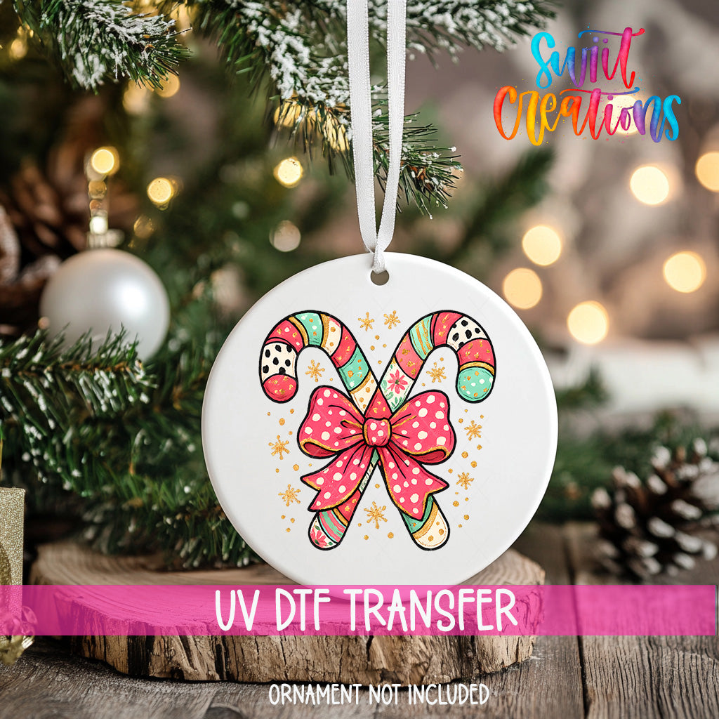 A white ceramic ornament with a colorful candy cane design and a pink bow, hanging on a Christmas tree.