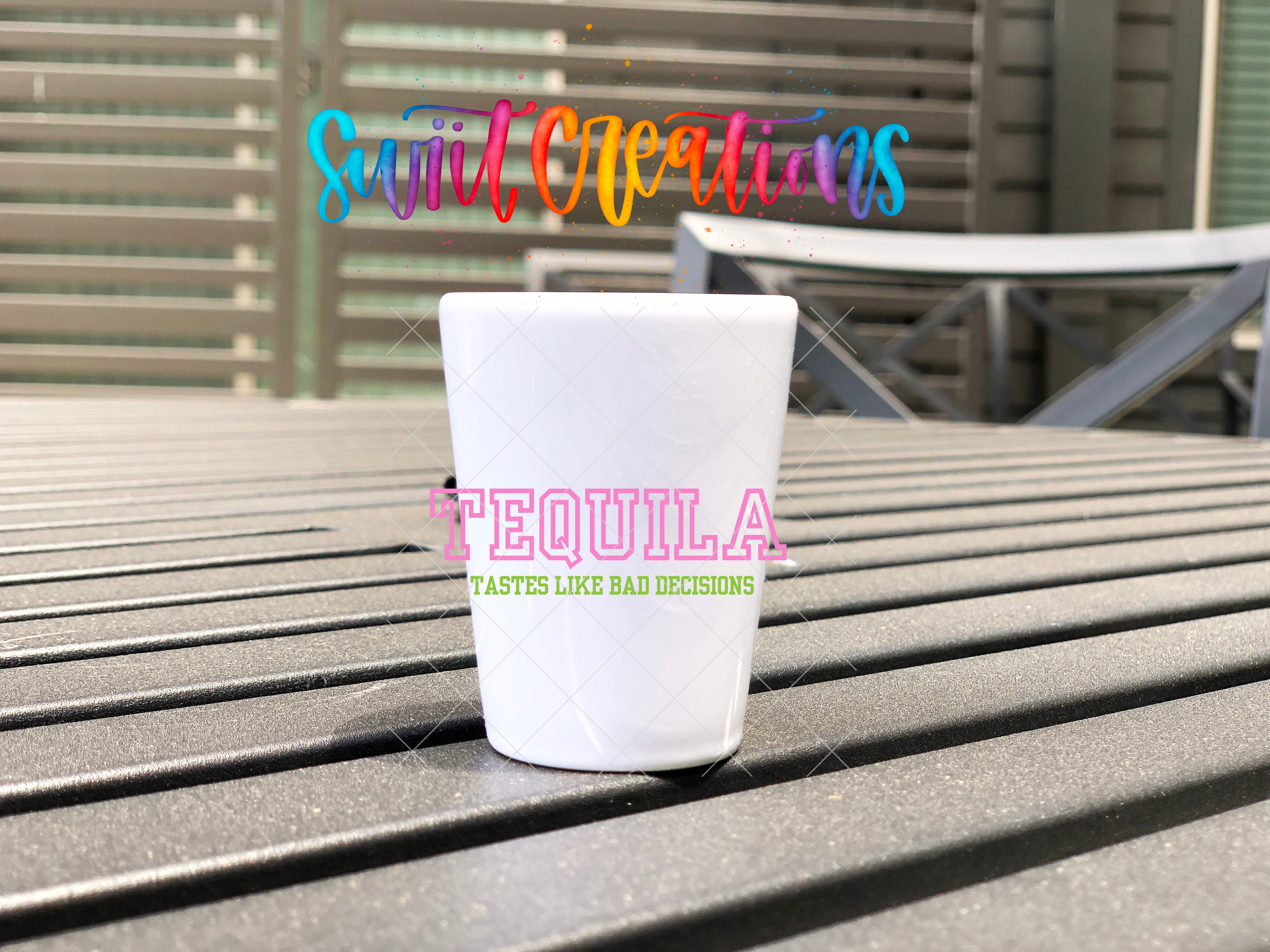 A white shot glass with the text "Tequila" and "Tastes like bad decisions" printed on it, placed on a wooden surface.