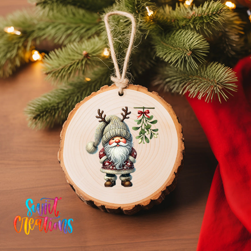 A wooden ornament featuring a gnome with antlers and a mistletoe is hanging on a Christmas tree.