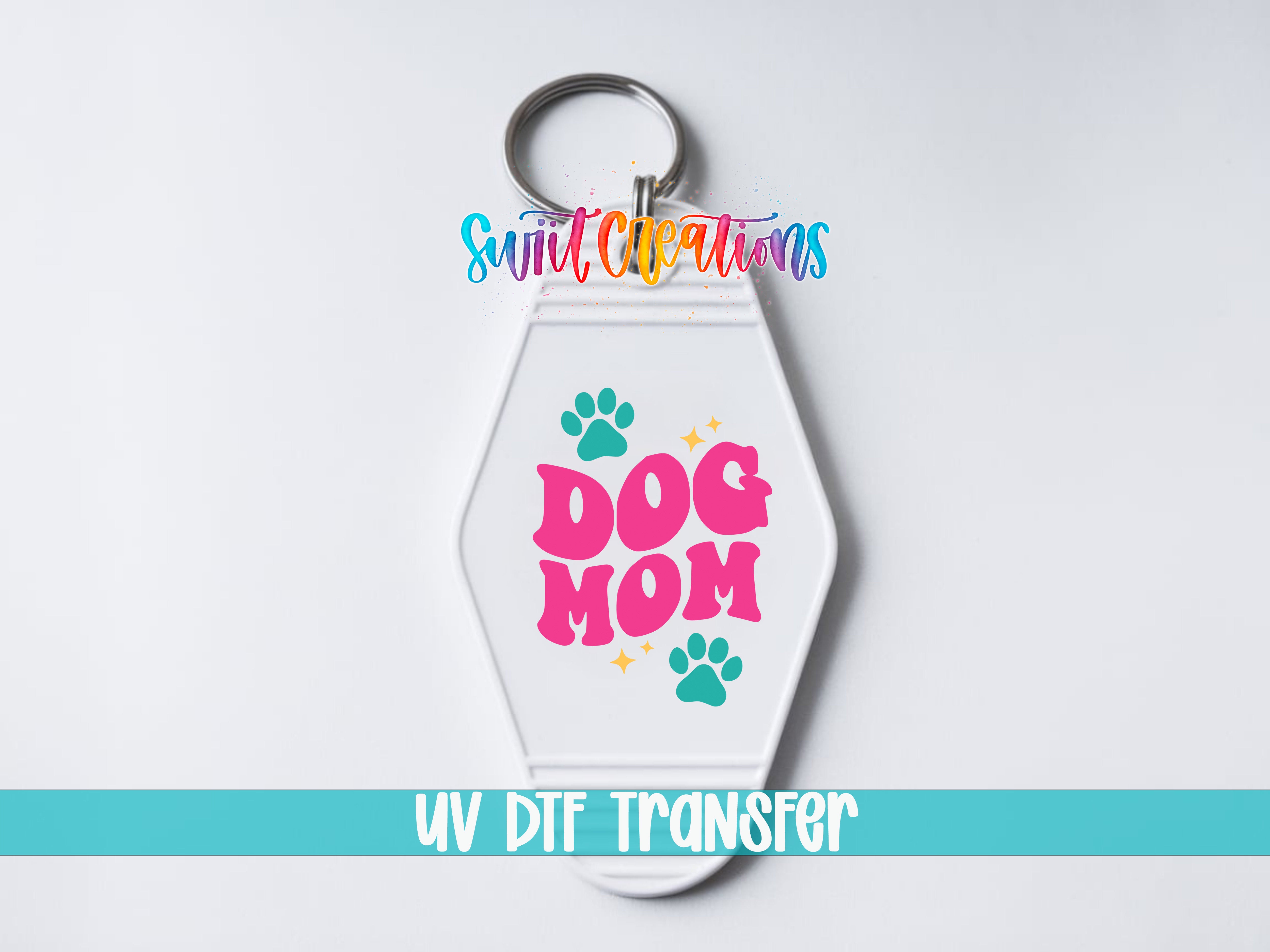 A keychain with the text "DOG MOM" and paw prints, along with the text "Sunlit Creations" and "UV DDF Transfer" printed on it.