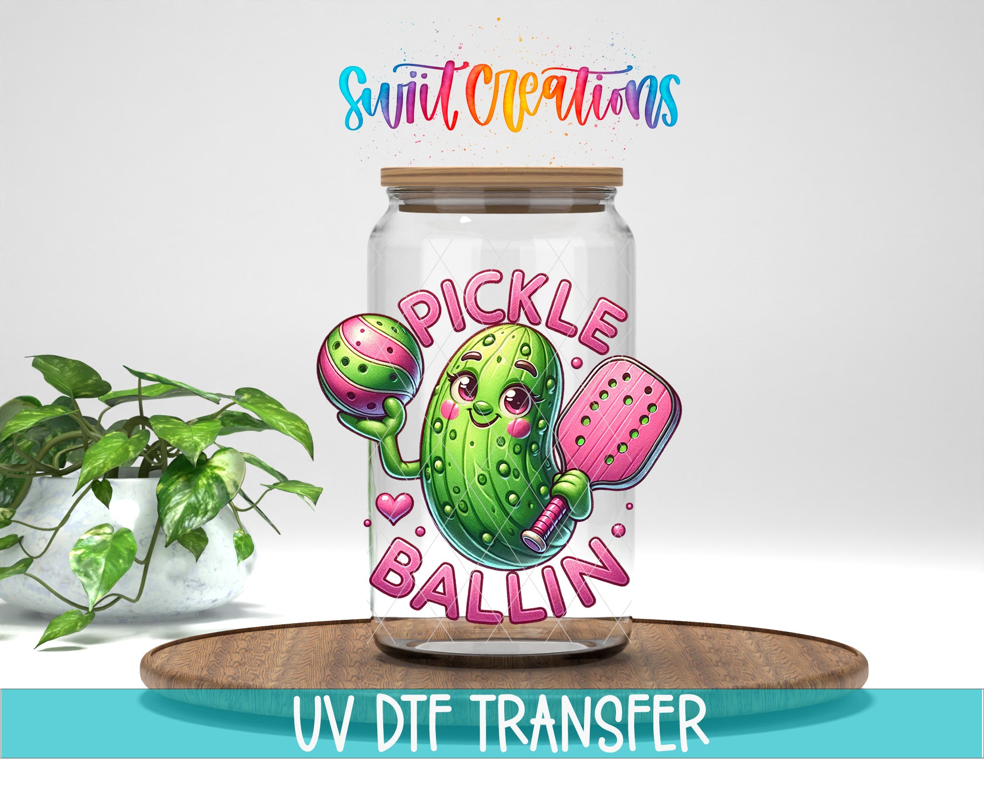 a glass jar with a label that says "Pickle Ballin" and a cartoon image of a pickle holding a ball and paddle. The jar is placed on a wooden surface, and there is a potted plant in the background.