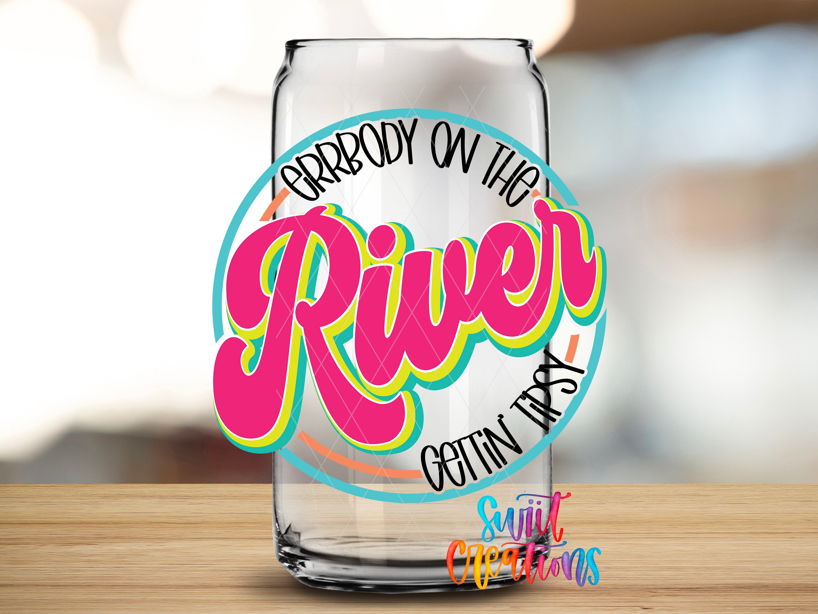 A glass can with a colorful, stylized text design on it, placed on a wooden surface.