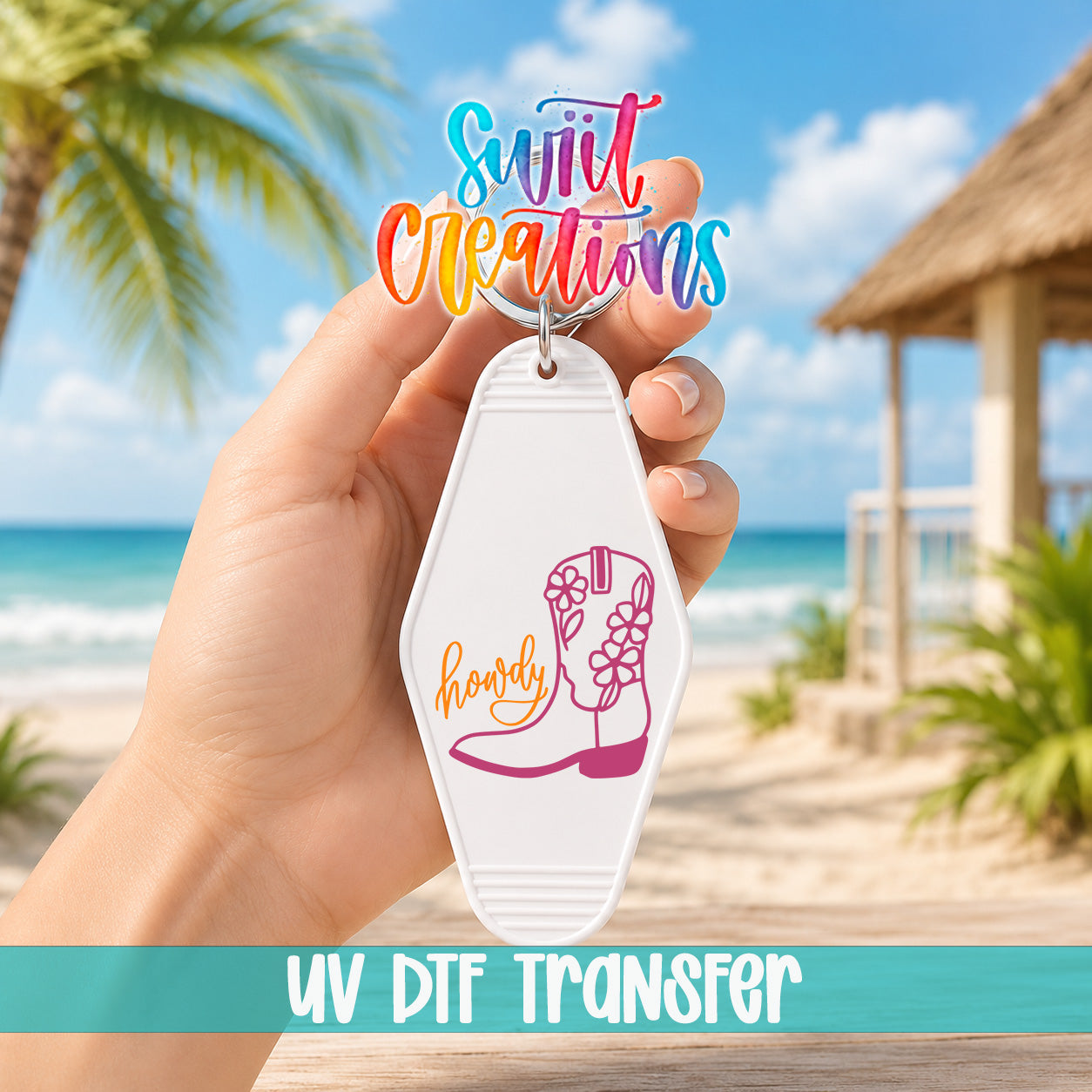 A hand holding a keychain with a colorful design and text, against a backdrop of a beach and palm trees.