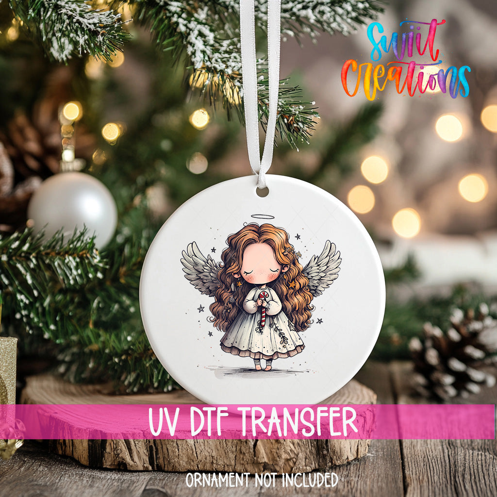 A white ceramic ornament with a cartoon illustration of a girl with long curly hair and wings, hanging on a Christmas tree.