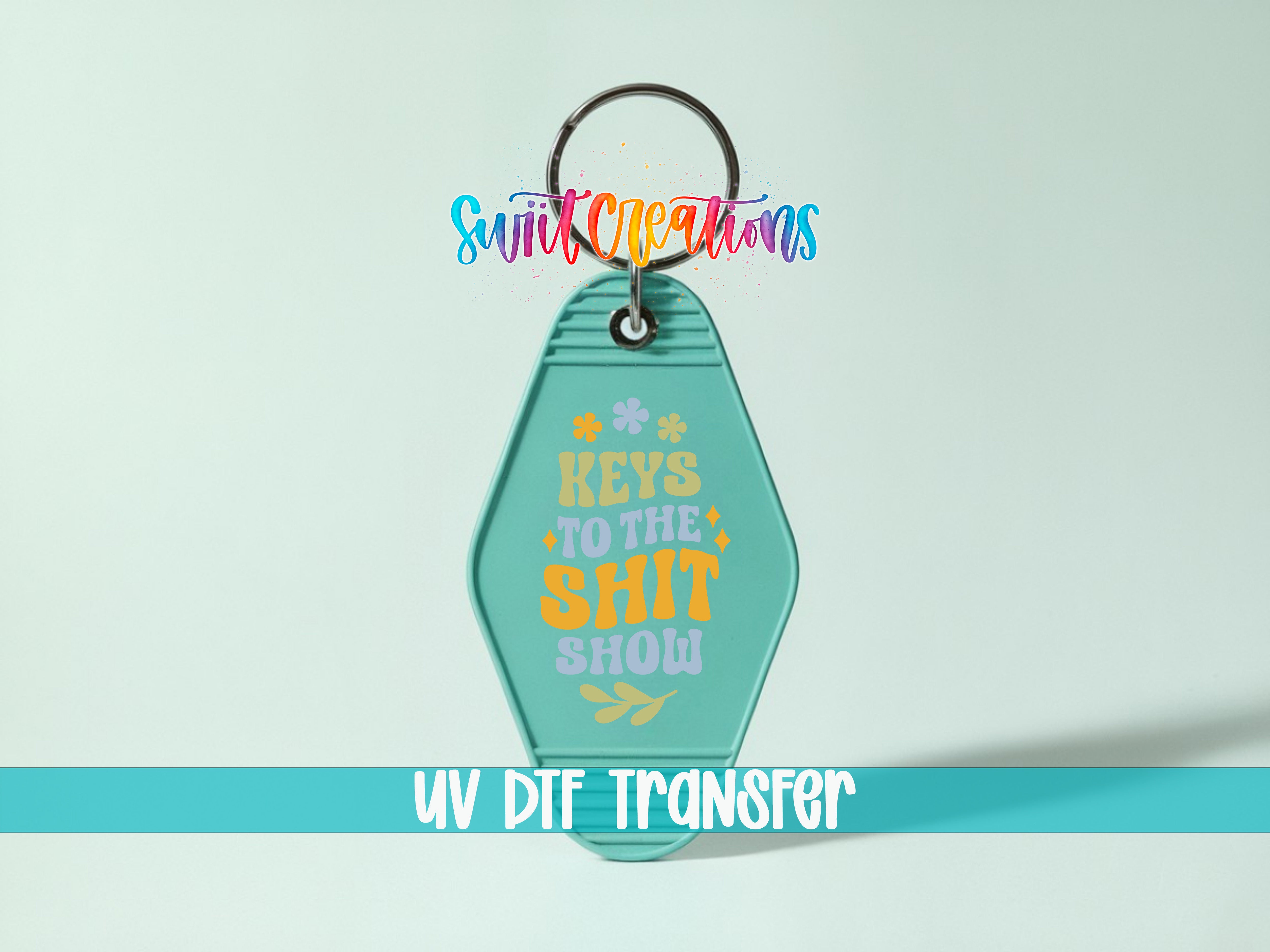 A keychain with the text "Keys to the shit show" printed on it, along with a colorful, stylized logo.