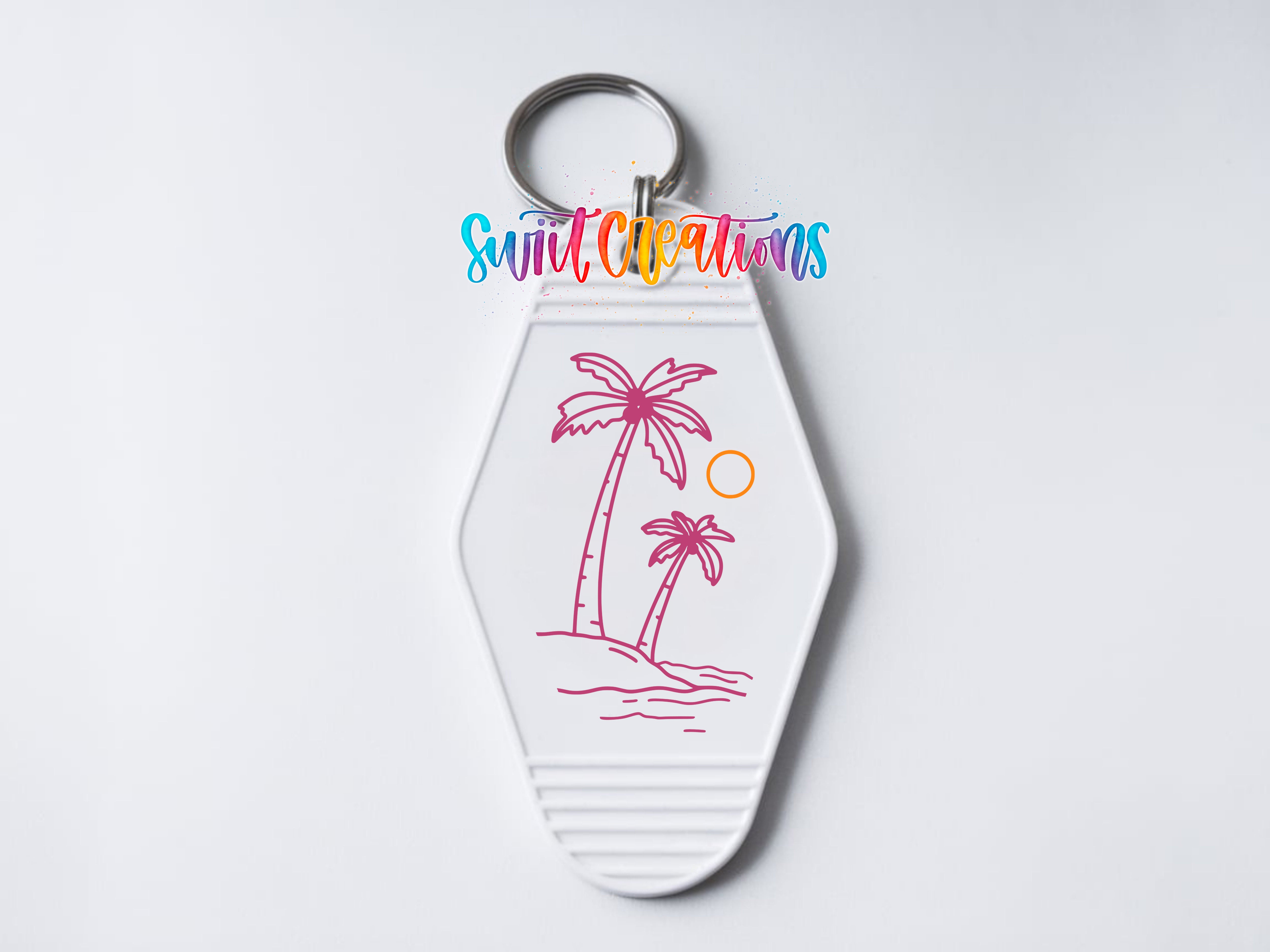 A keychain with a palm tree and sun design, along with the text "Sunlit Creations" written on it.