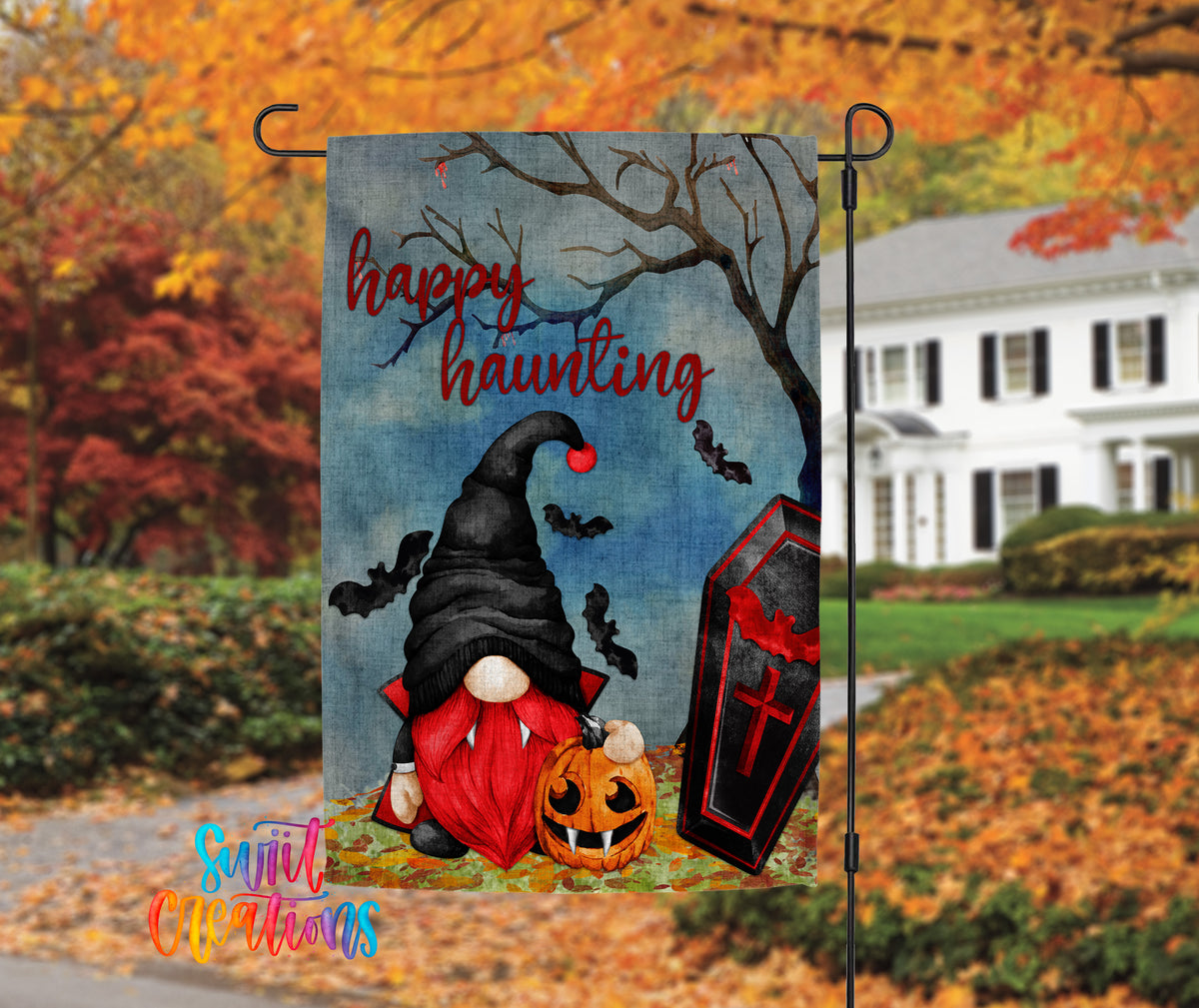 A Halloween-themed garden flag featuring a gnome, a pumpkin, bats, and a casket, with the text "Happy haunting" displayed.