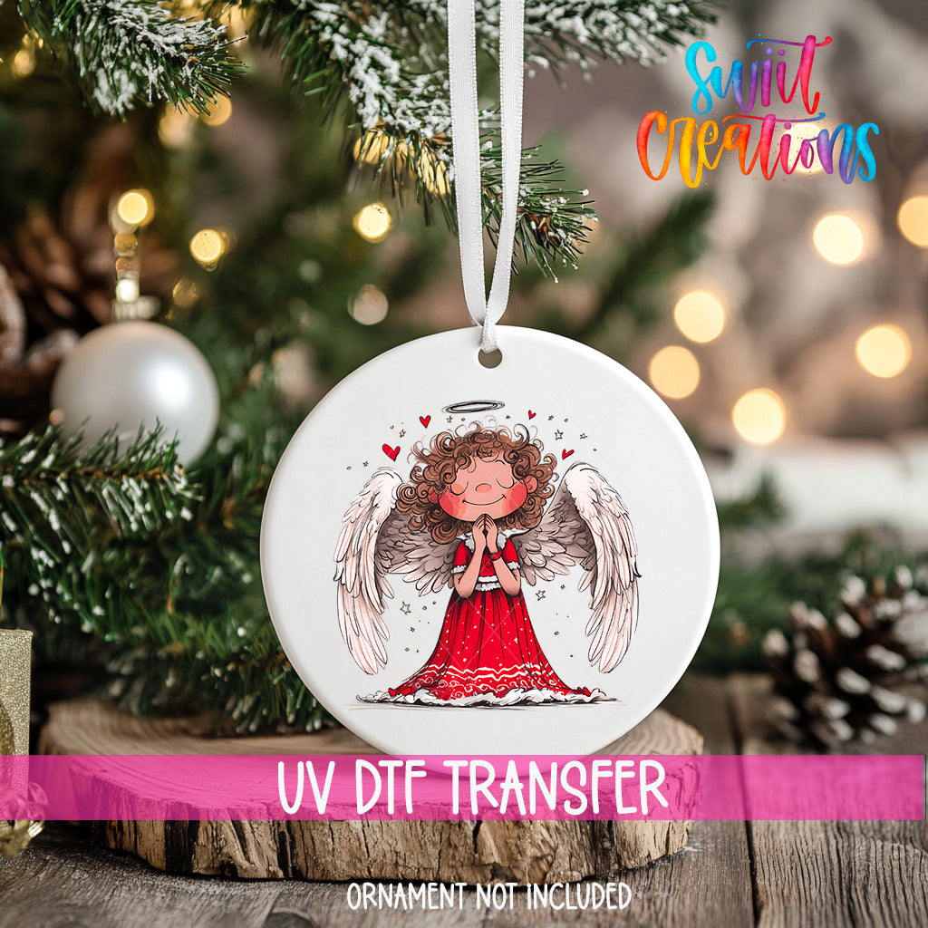 A white ceramic ornament with a smiling angel design hangs on a Christmas tree.