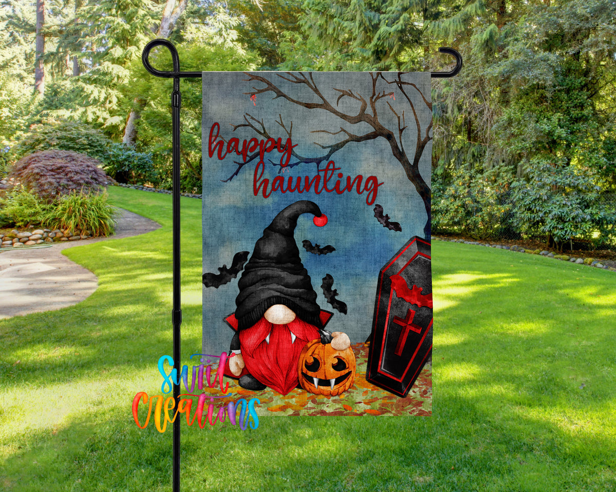 A Halloween-themed garden flag featuring a gnome, a skull, and a pumpkin, with the text "Happy Haunting" displayed prominently.