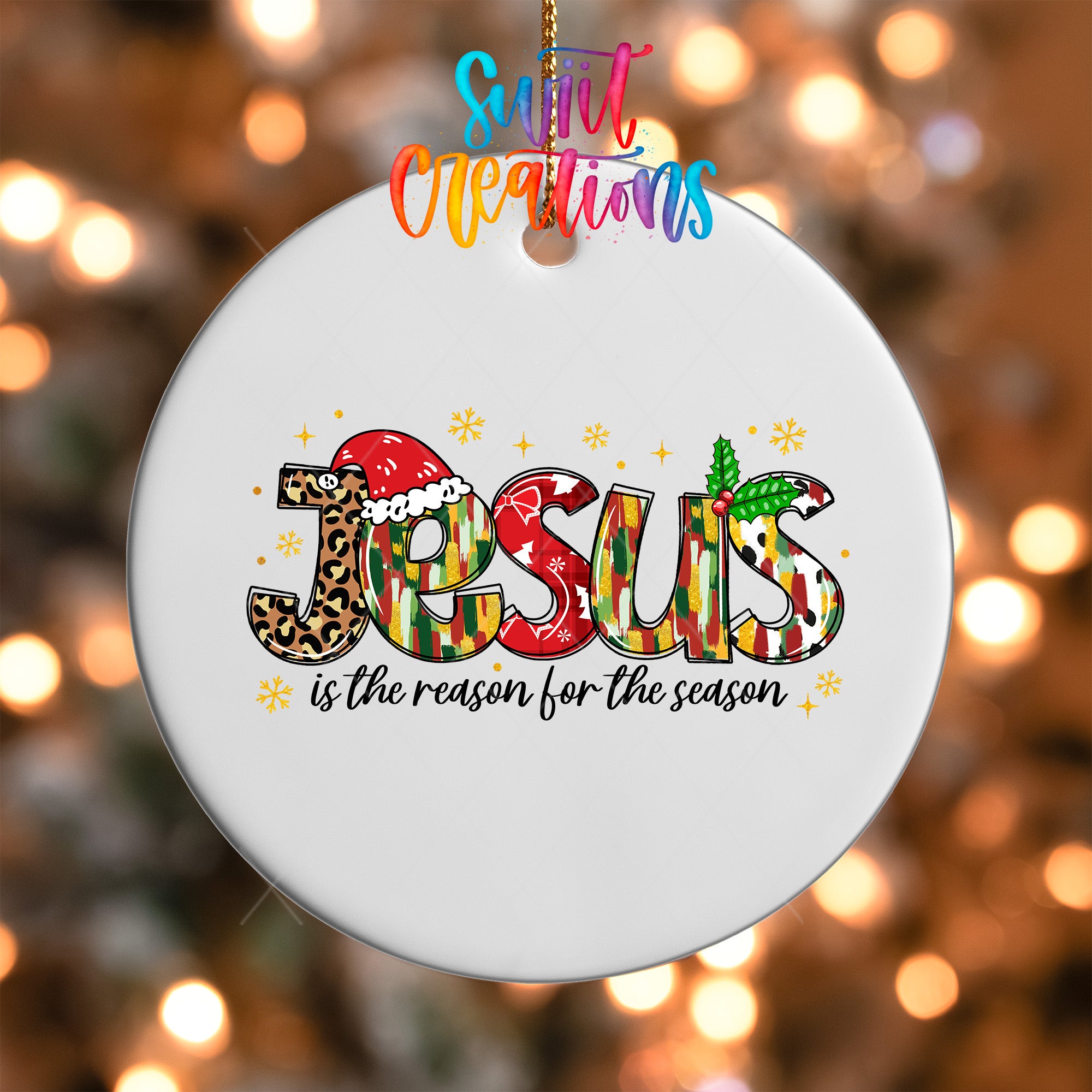 A white ornament with the word "JESUS" written in a colorful, stylized font, surrounded by snowflakes and other festive decorations.