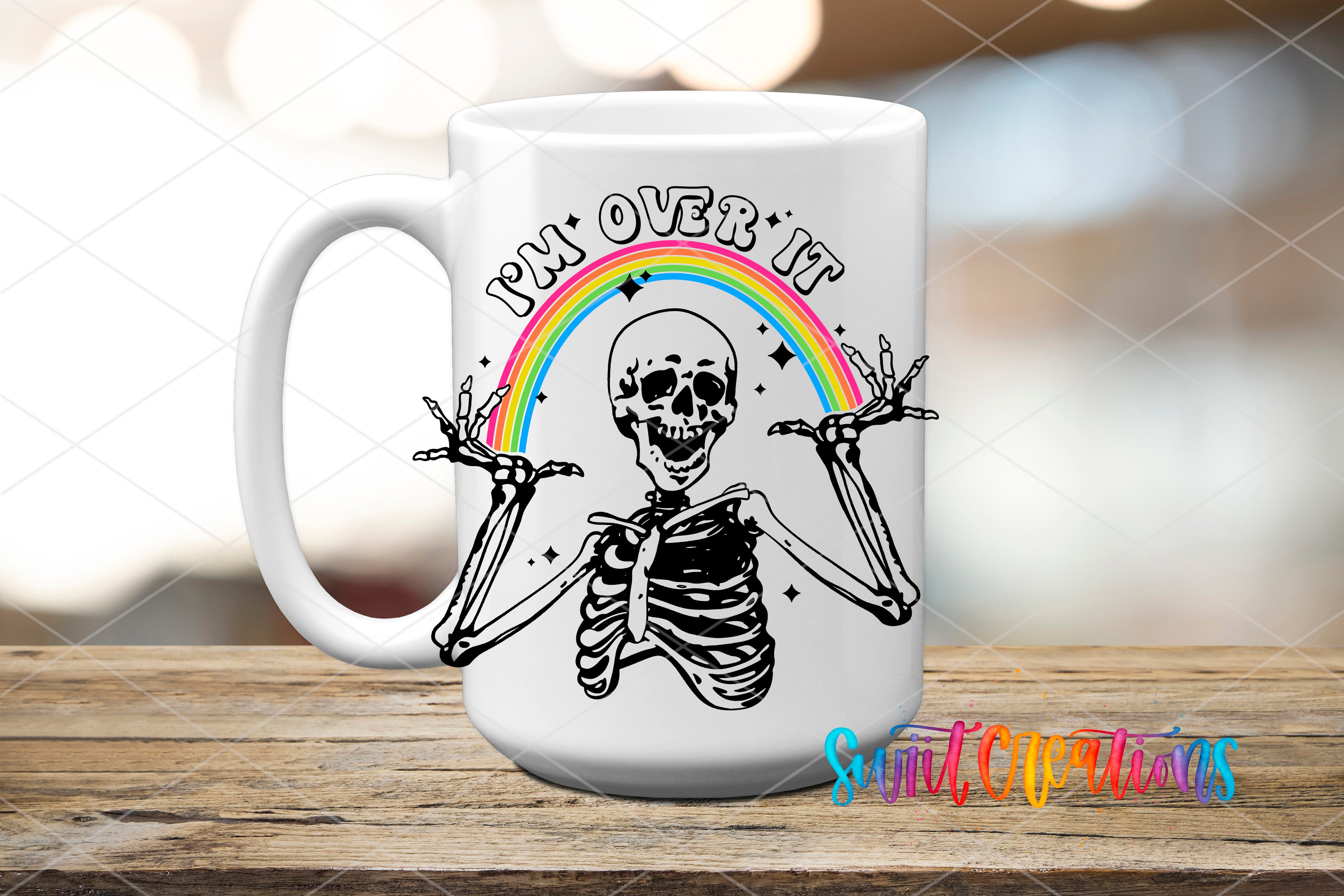 A white ceramic mug with a black and white illustration of a skeleton with outstretched arms and a rainbow arching above it.