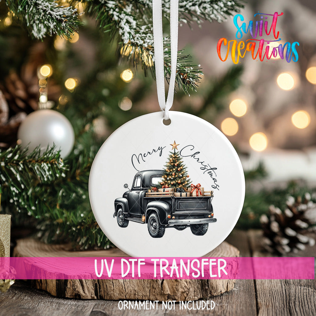 A white ceramic ornament with a black and white illustration of a truck carrying a Christmas tree and presents, hanging on a Christmas tree.